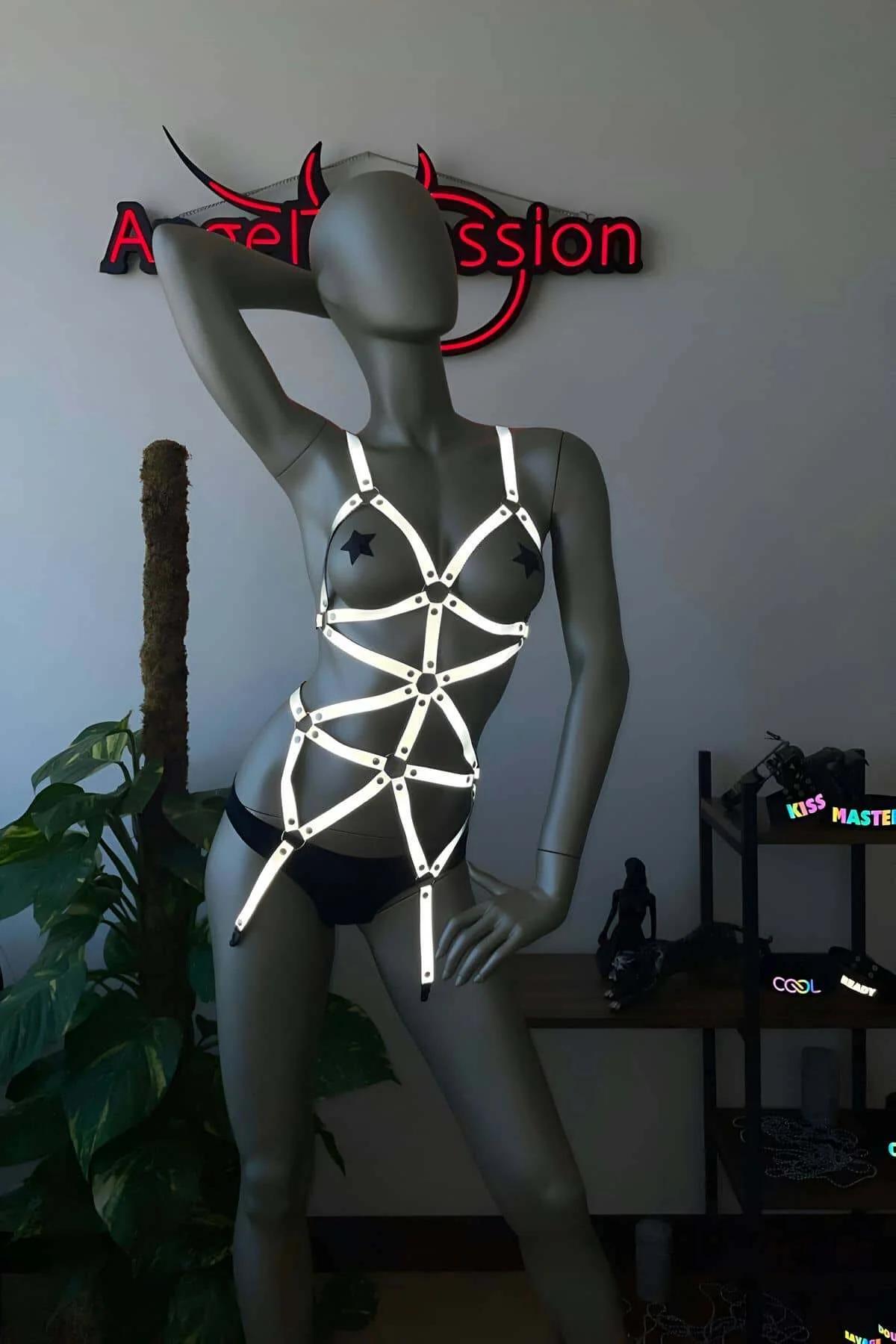 Reflective full body harness worn over bare skin showing geometric coverage from chest to hip in low-light setting