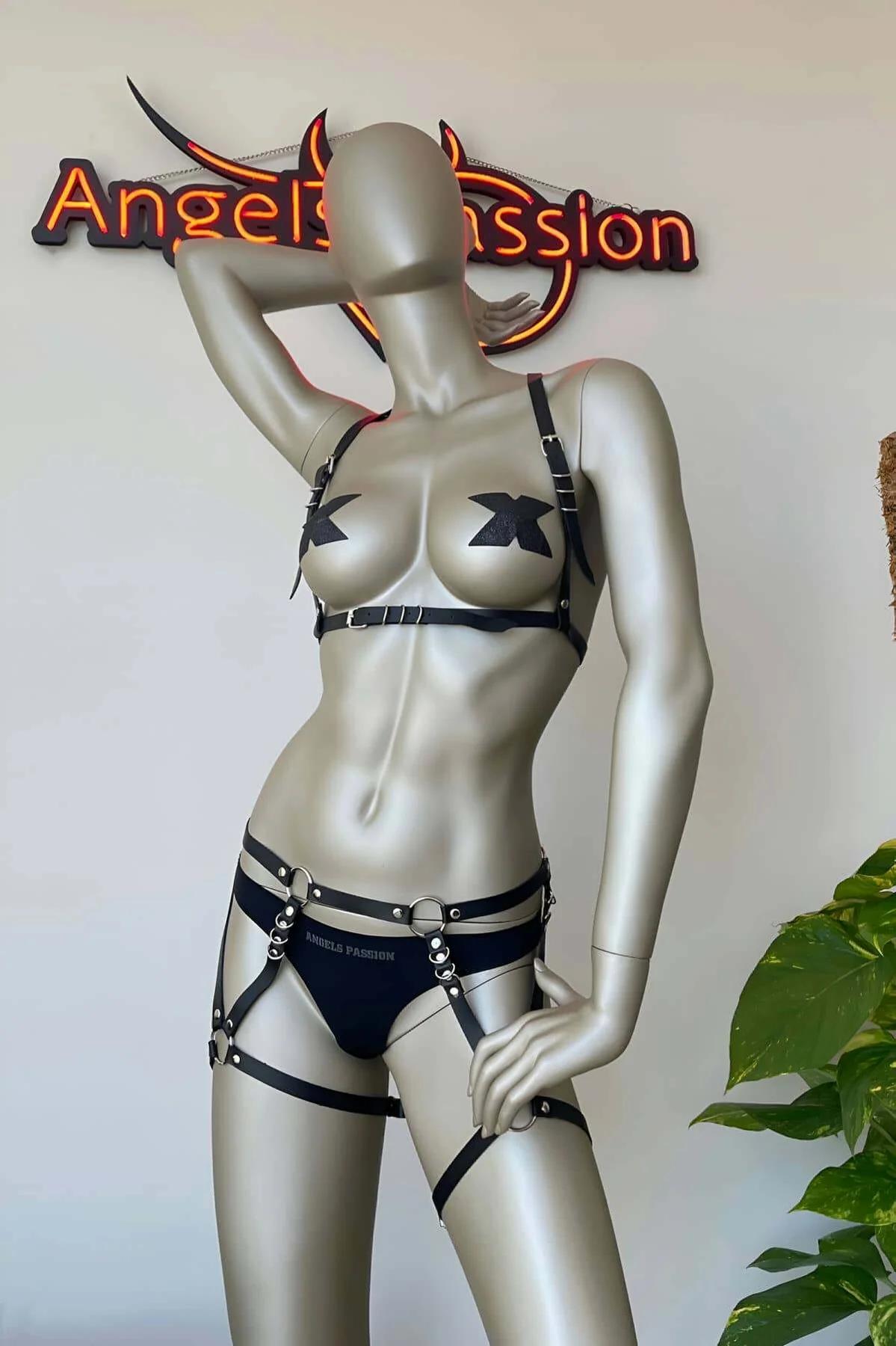 Studded black faux leather brief with silver stud waistband and D-ring hip attachment points, close-up