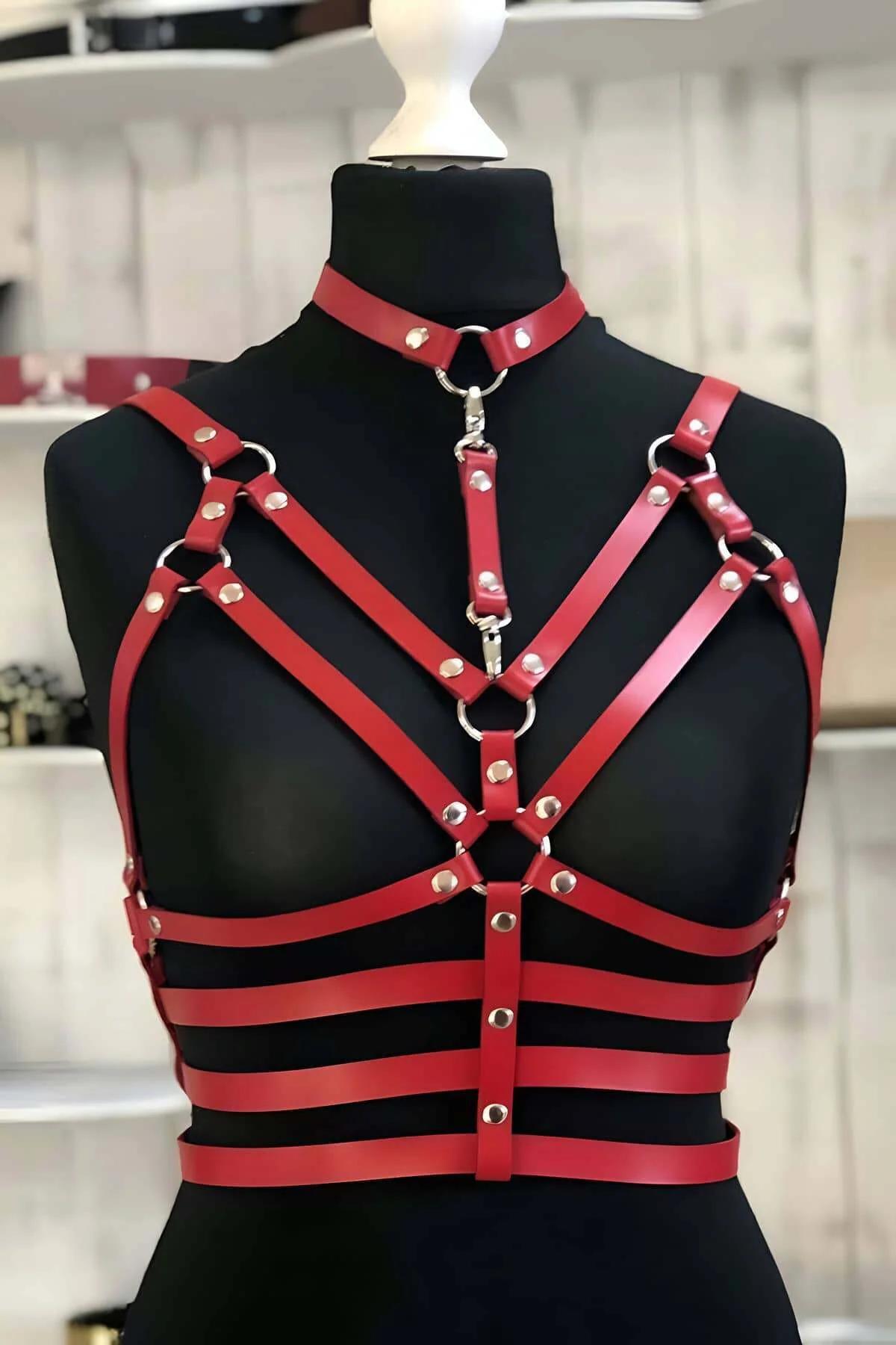 Red faux leather harness front view showing triangular cage strap layout with silver dome studs