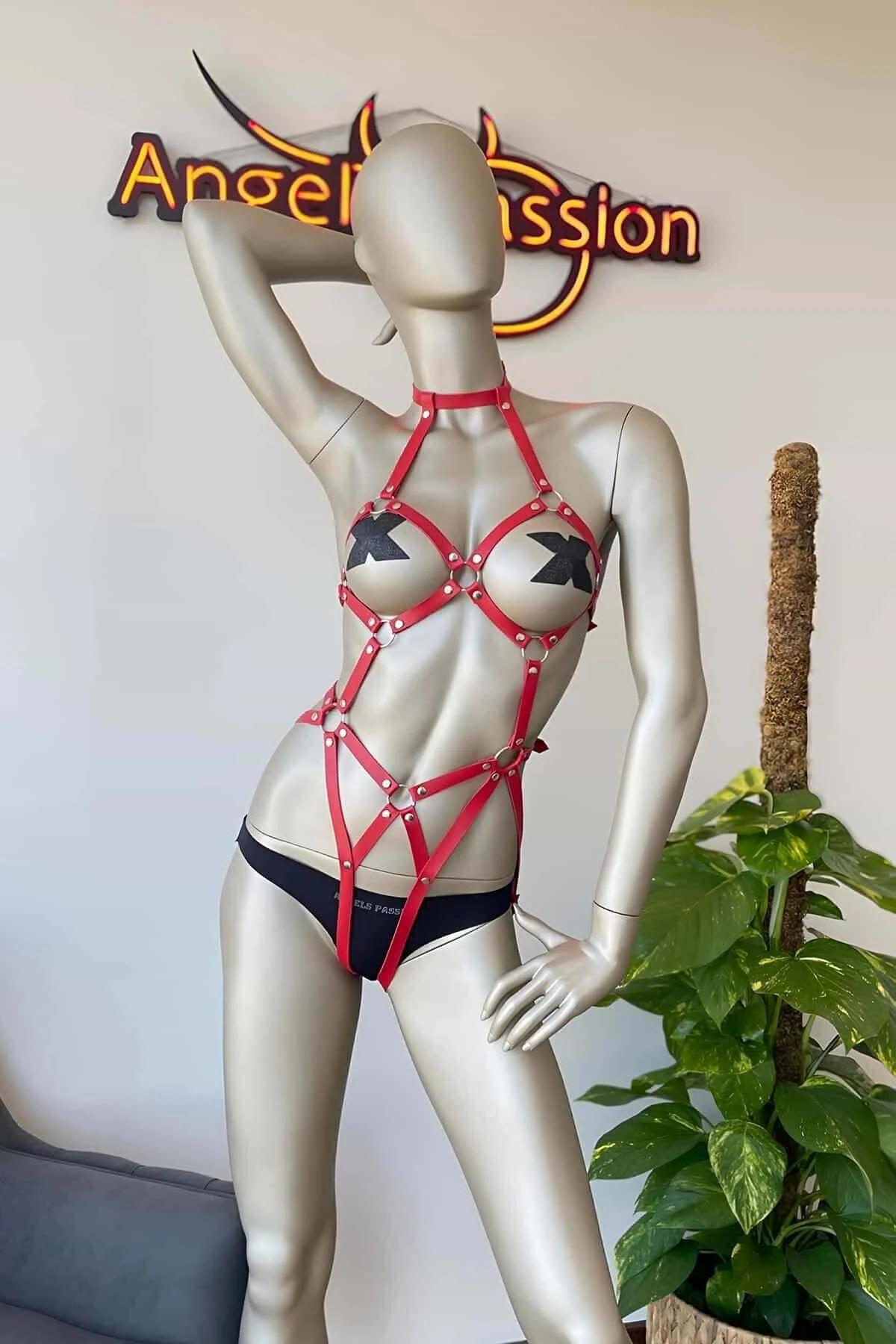 Close-up of silver O-ring and dome stud intersections on red faux leather cage harness straps