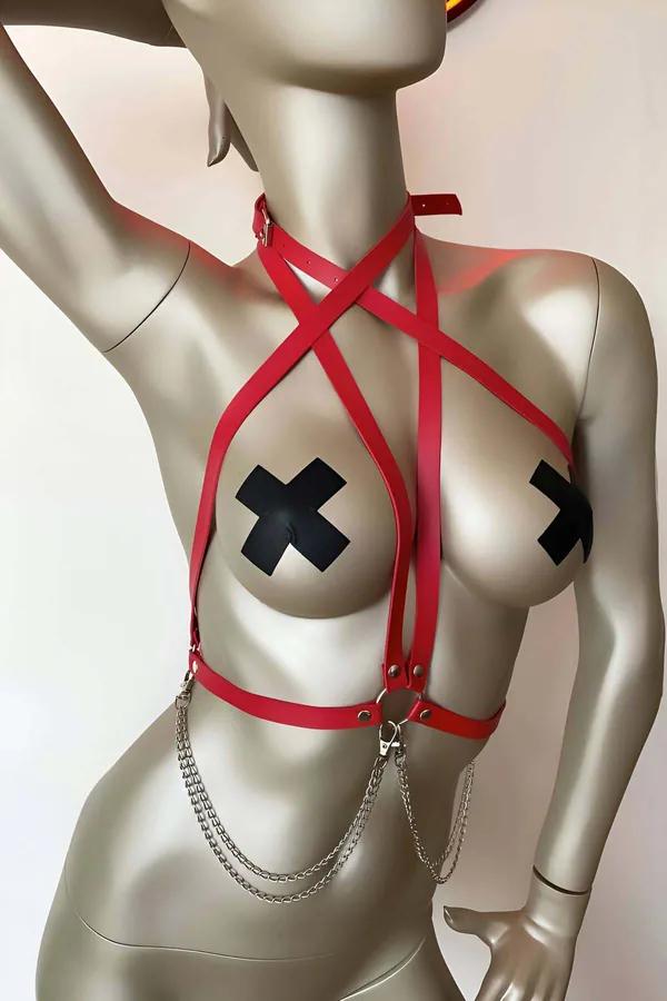 Red faux leather strappy body harness with cross-X chest strap geometry and multi-strand silver chain detail on silver manneq