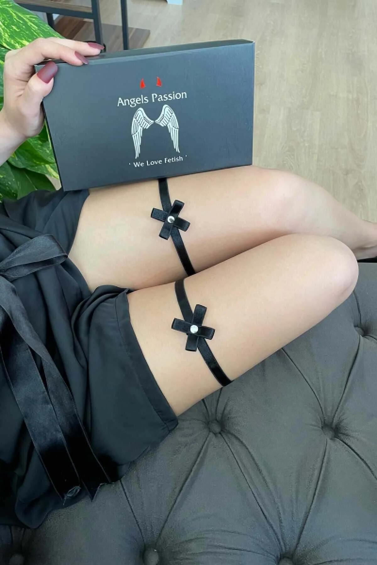 Close-up of black satin bow garter with white faux-pearl bead center on upper thigh