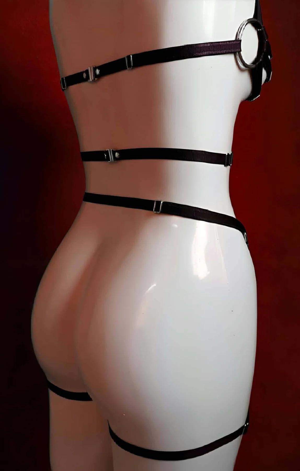 Full torso black harness layered over skin showing stretch band width and gold metal hardware