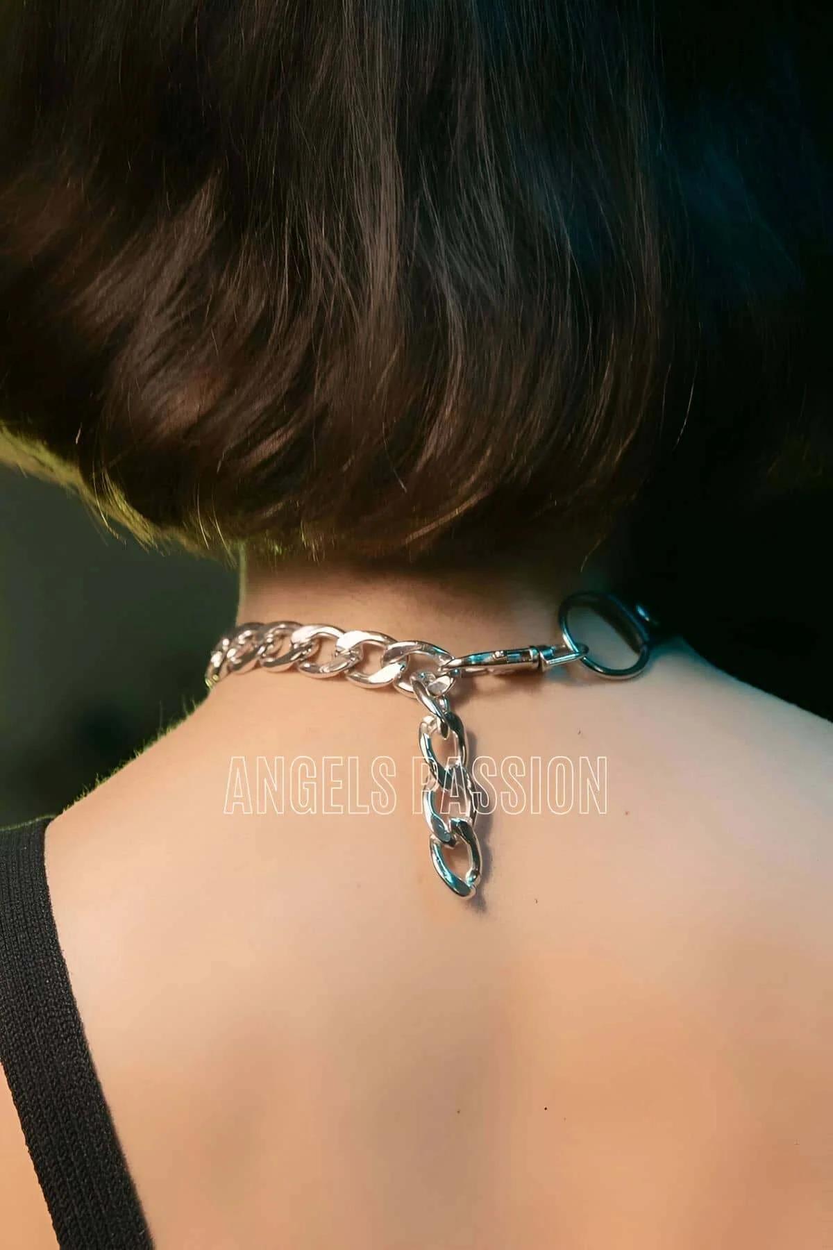 Close-up of silver O-ring and curb chain links on black faux leather choker band