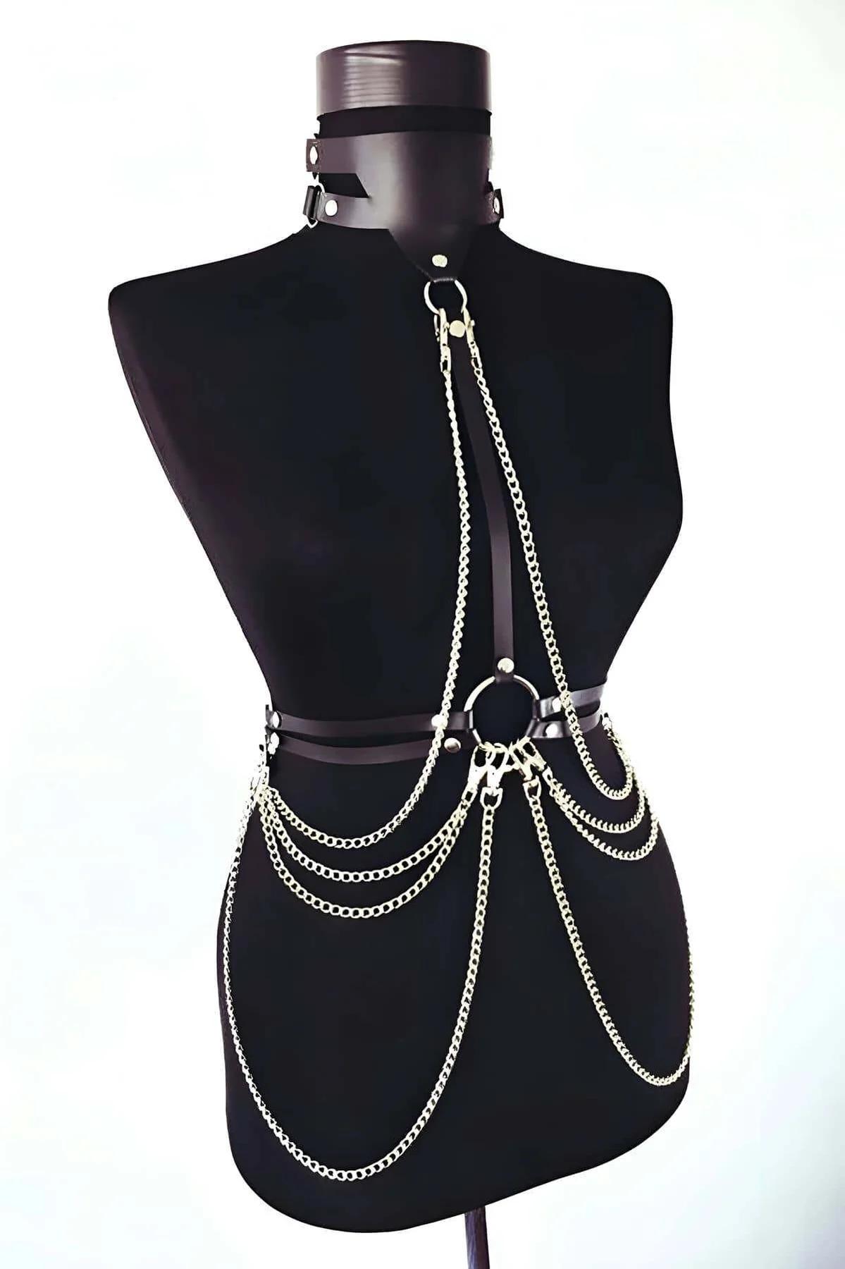 Close-up of gold-tone O-ring and faux leather waist straps on black chain body harness