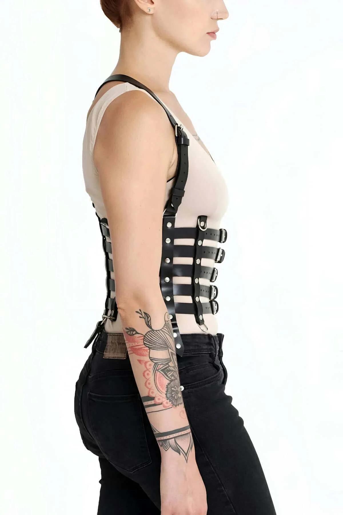 detail of adjustable strap holes on black faux leather underbust corset harness with silver buckle