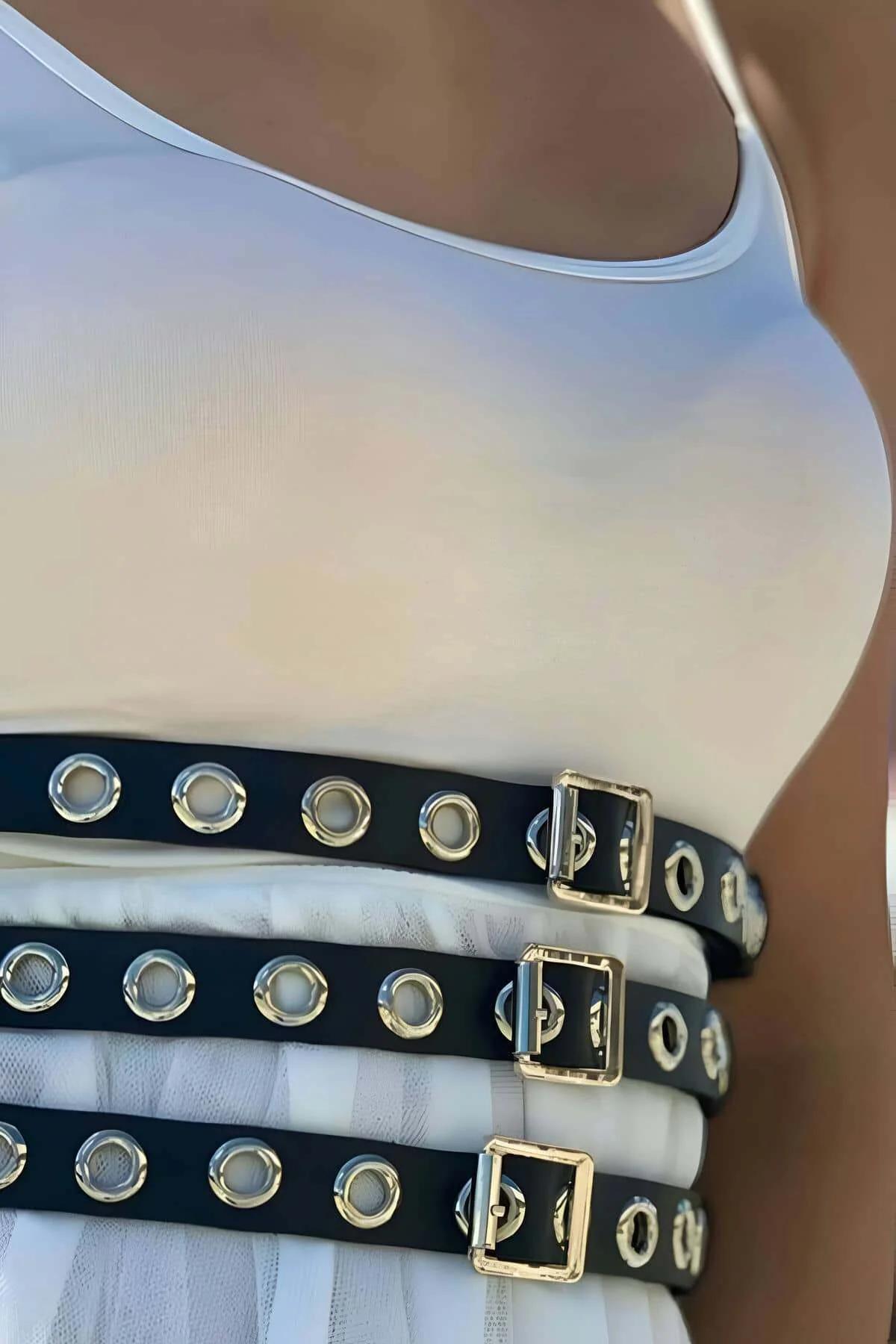 Adjustable black faux leather waist harness with grommets styled over white midi dress