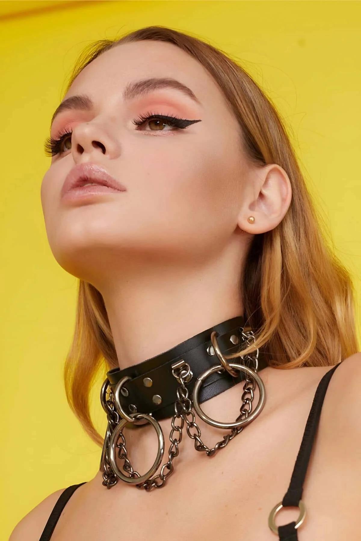 Close-up of three gunmetal O-rings riveted on wide black faux leather choker band