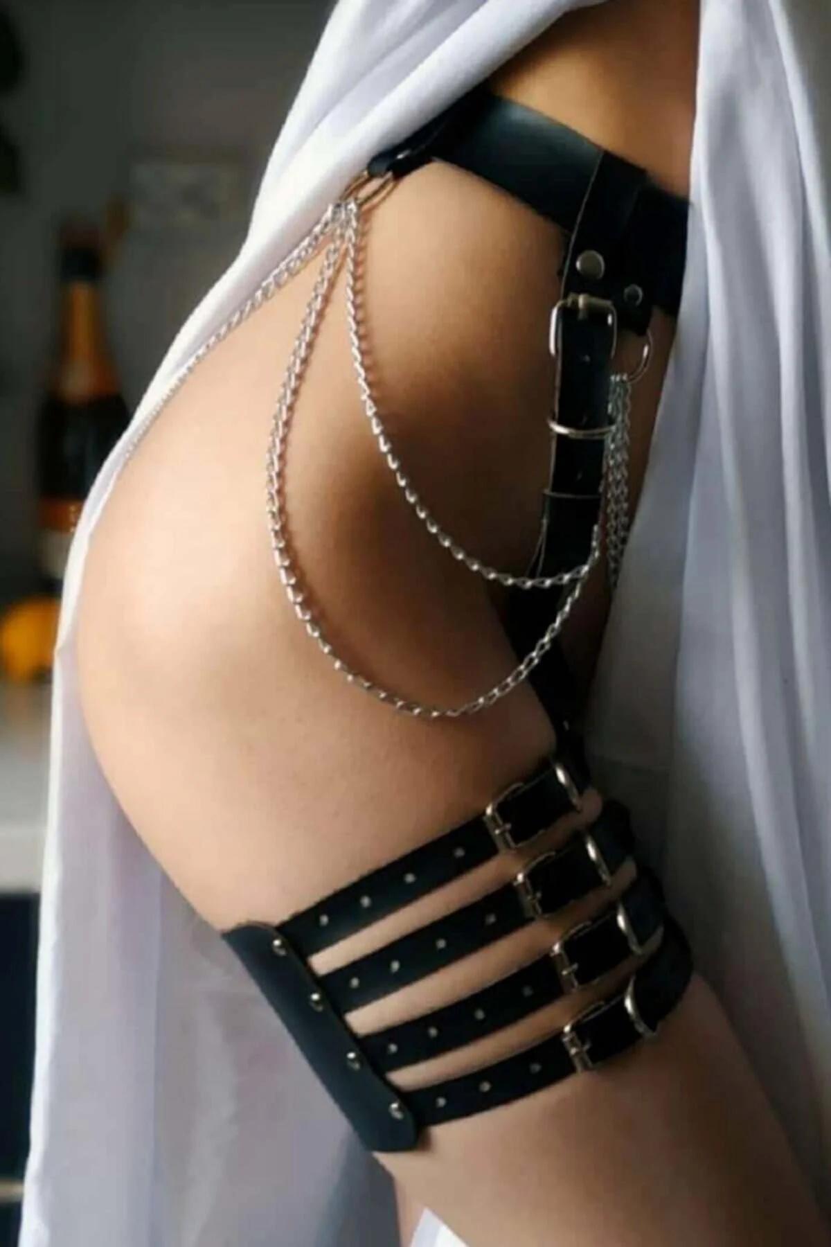 Black faux leather garter harness with four silver buckle cage straps and three draped silver chains on thigh