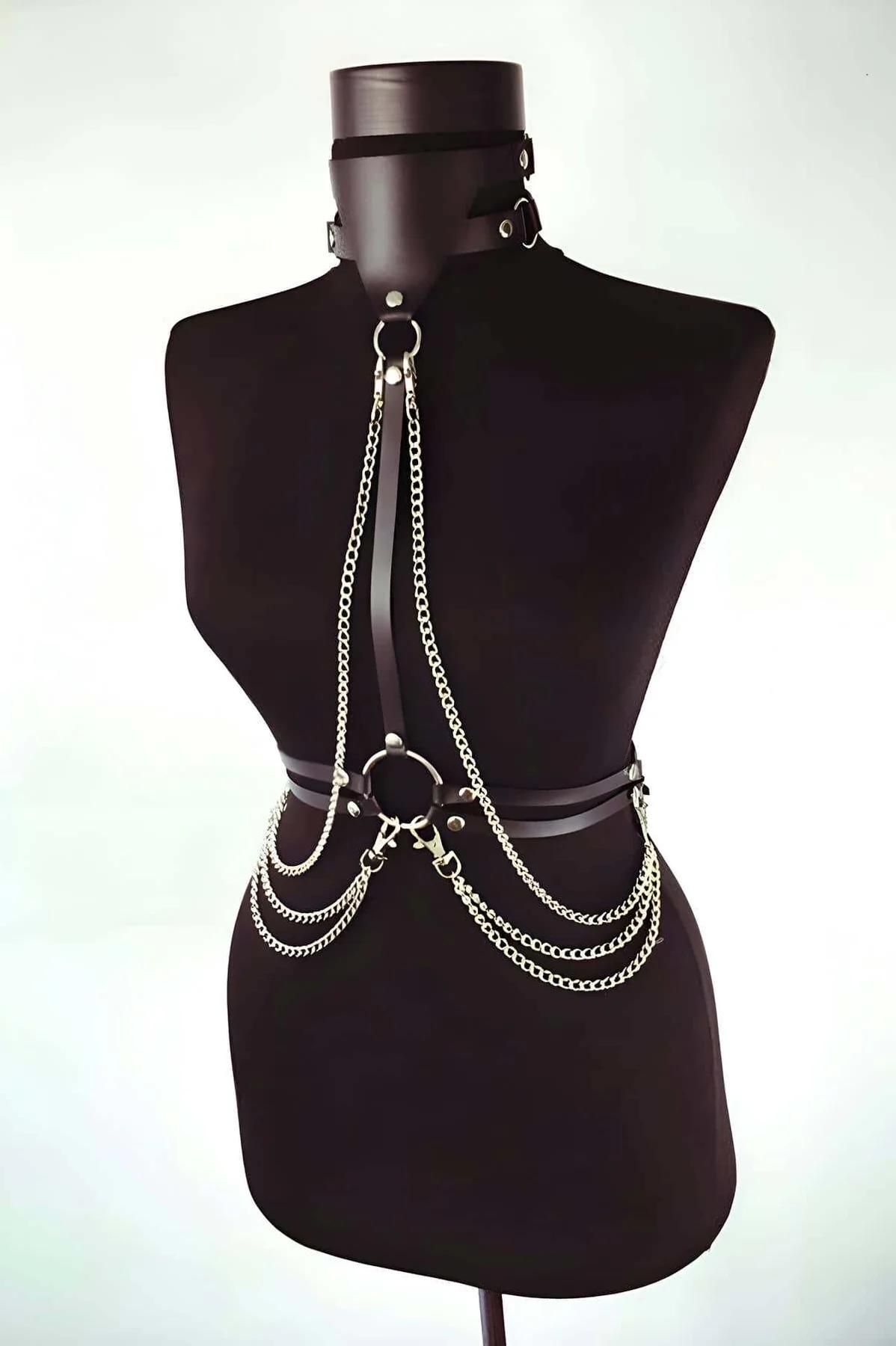 Close-up of gold-tone curb-link chains and lobster-claw clasps on black faux leather waist band