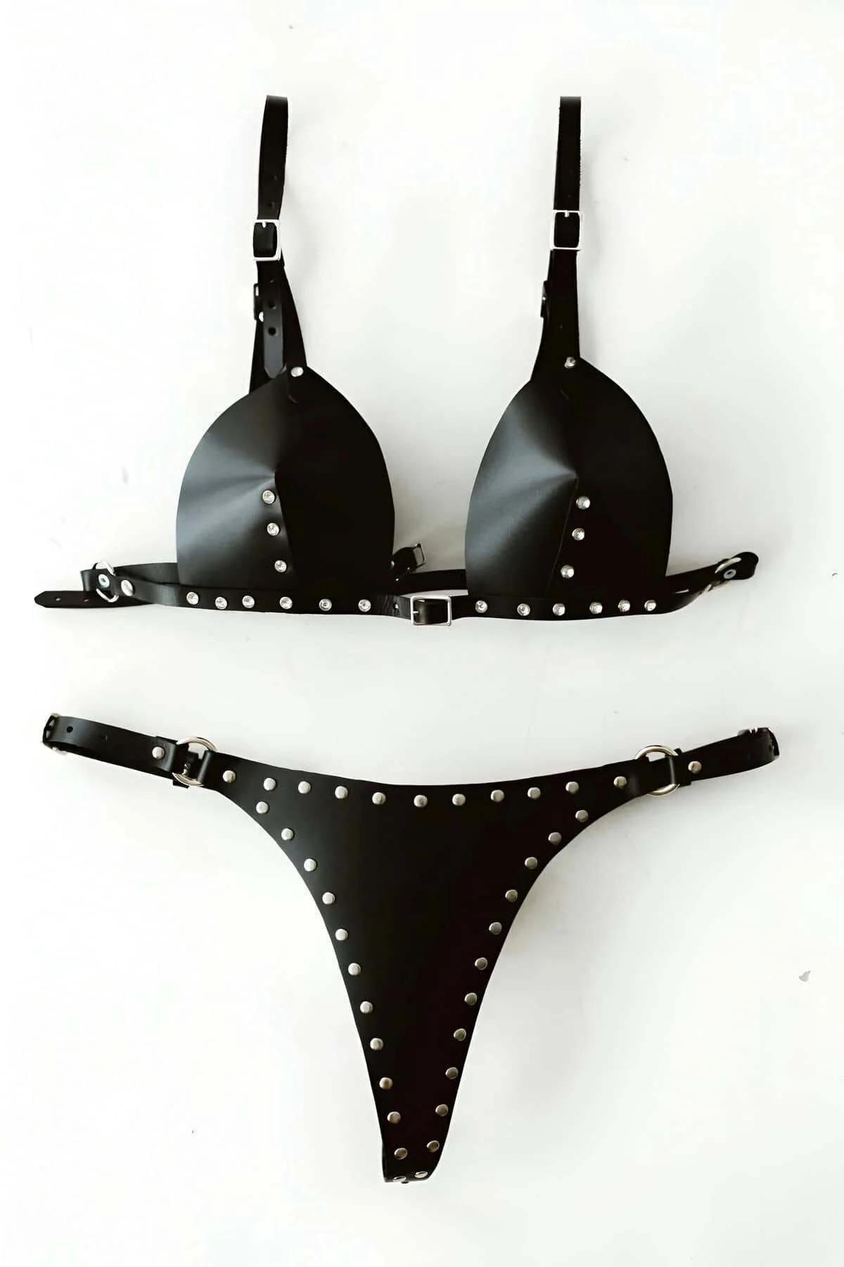Close-up of silver dome studs on black faux leather bra cup and midriff strap detail