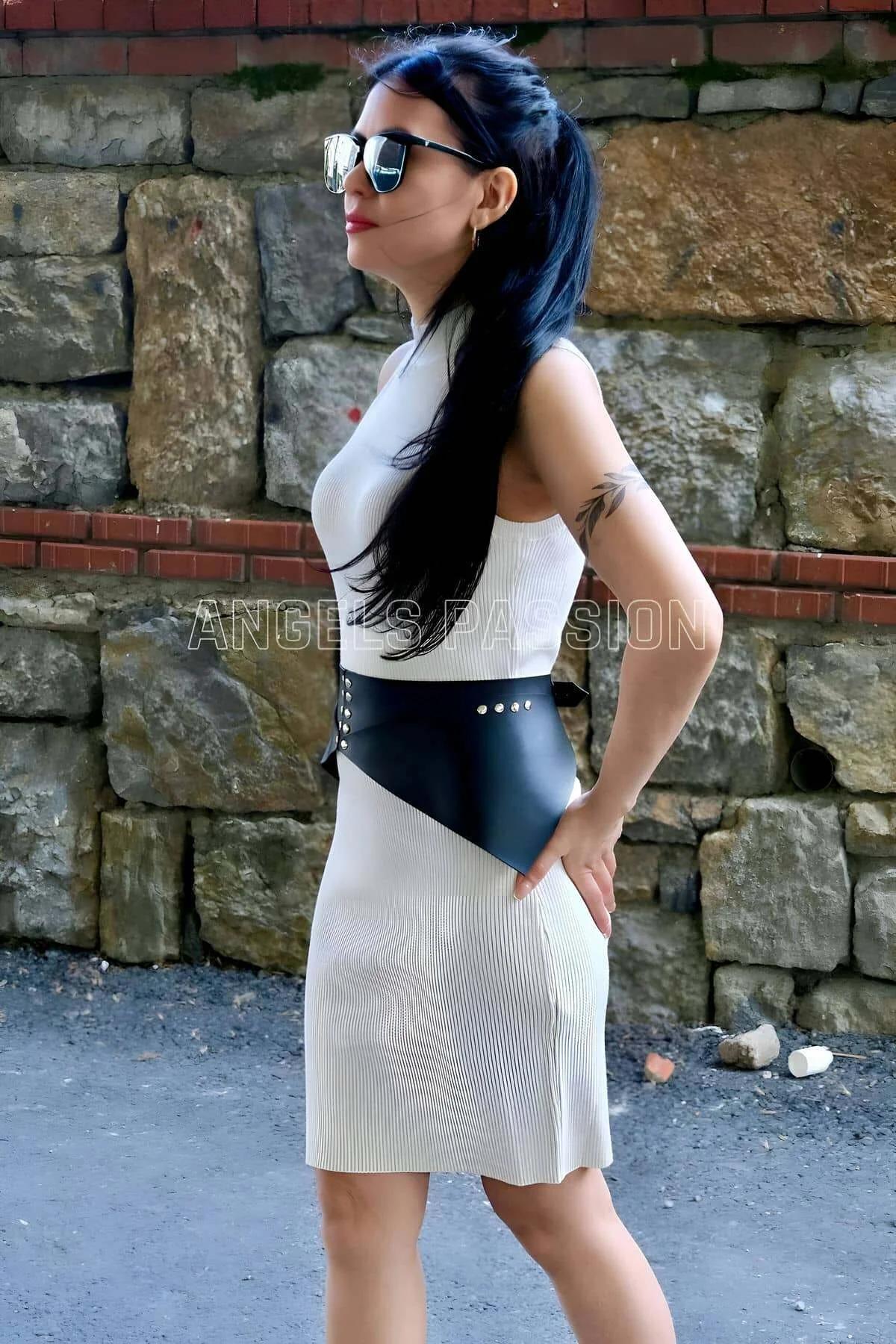 Black faux leather rivet studded harness styled over fitted white bodycon midi dress