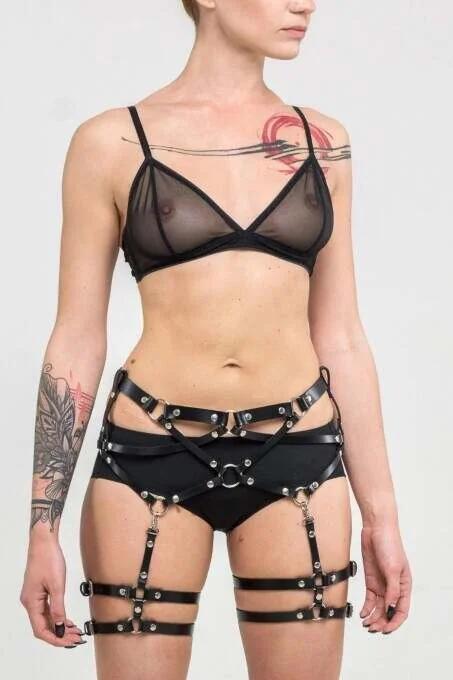 close-up of silver O-ring and metal pin buckles on black faux leather thigh harness straps