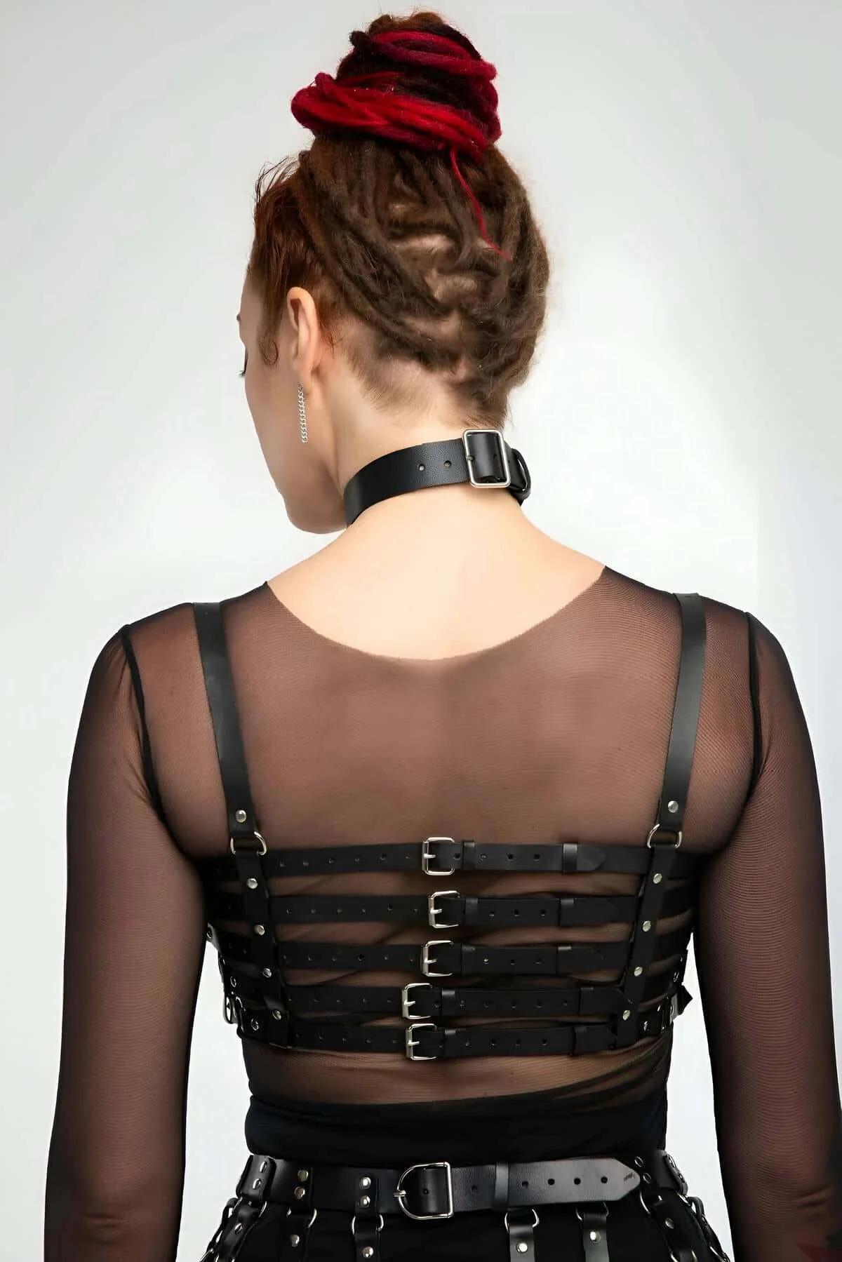 full body view of three-piece black faux leather harness set worn over sheer mesh top