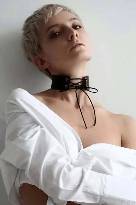 Close-up of corset lace-up front panel with four silver metal grommets on black faux leather choker