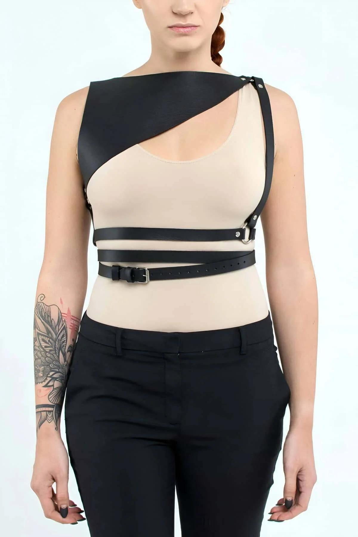 Flat lay of black asymmetric faux leather chest harness with waist straps fully extended showing full adjustable range
