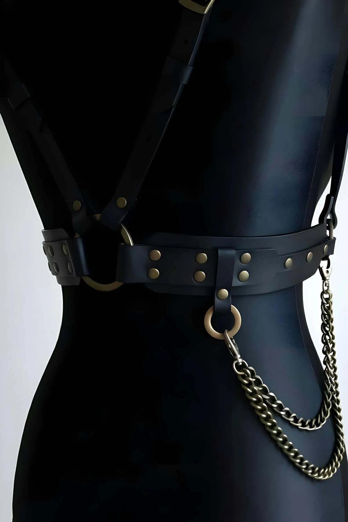 Black faux leather chest harness front view showing V-shaped shoulder straps and underbust band with bronze hardware