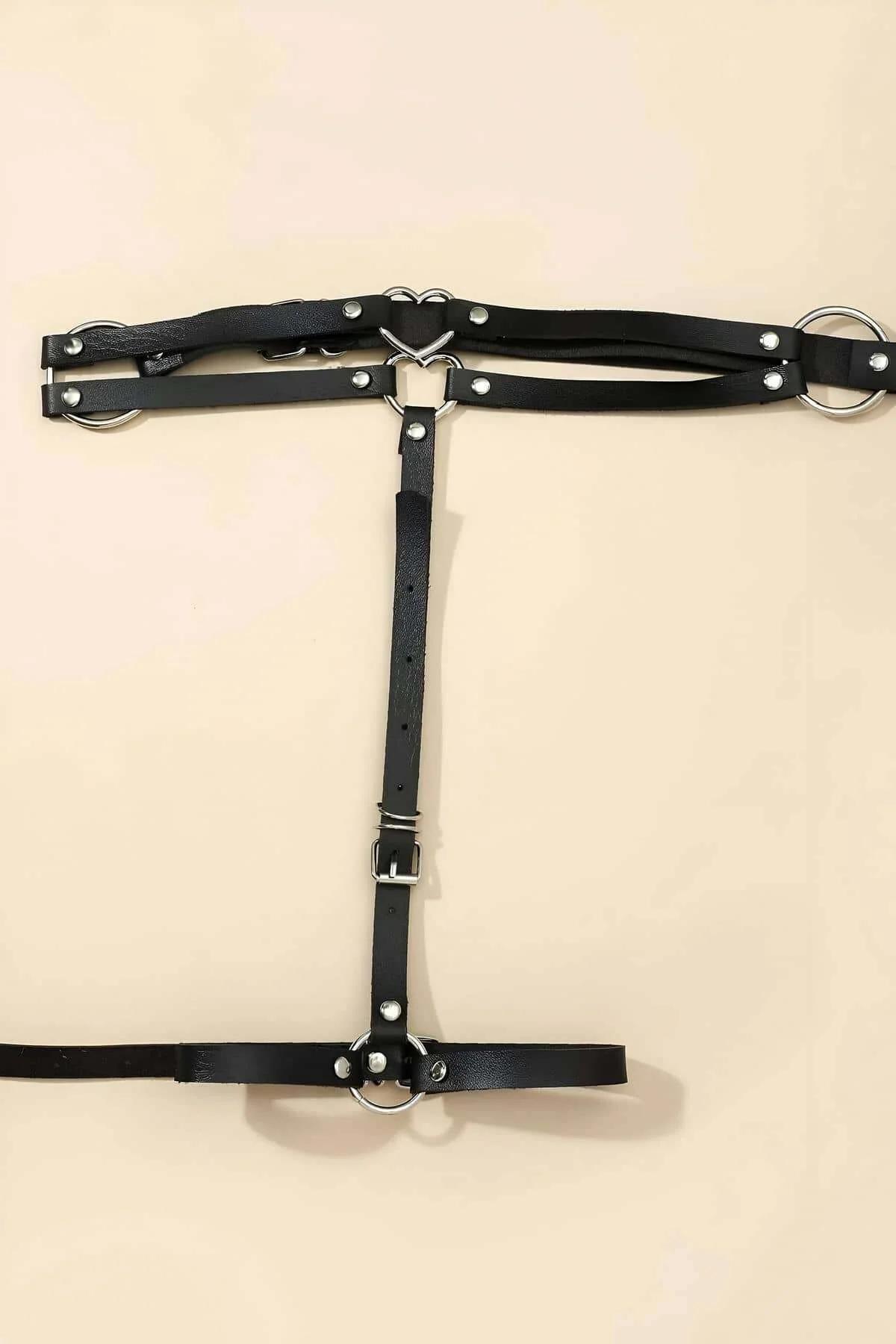 Close-up of silver heart-shaped center ring and rivet studs on black PU leather garter harness straps