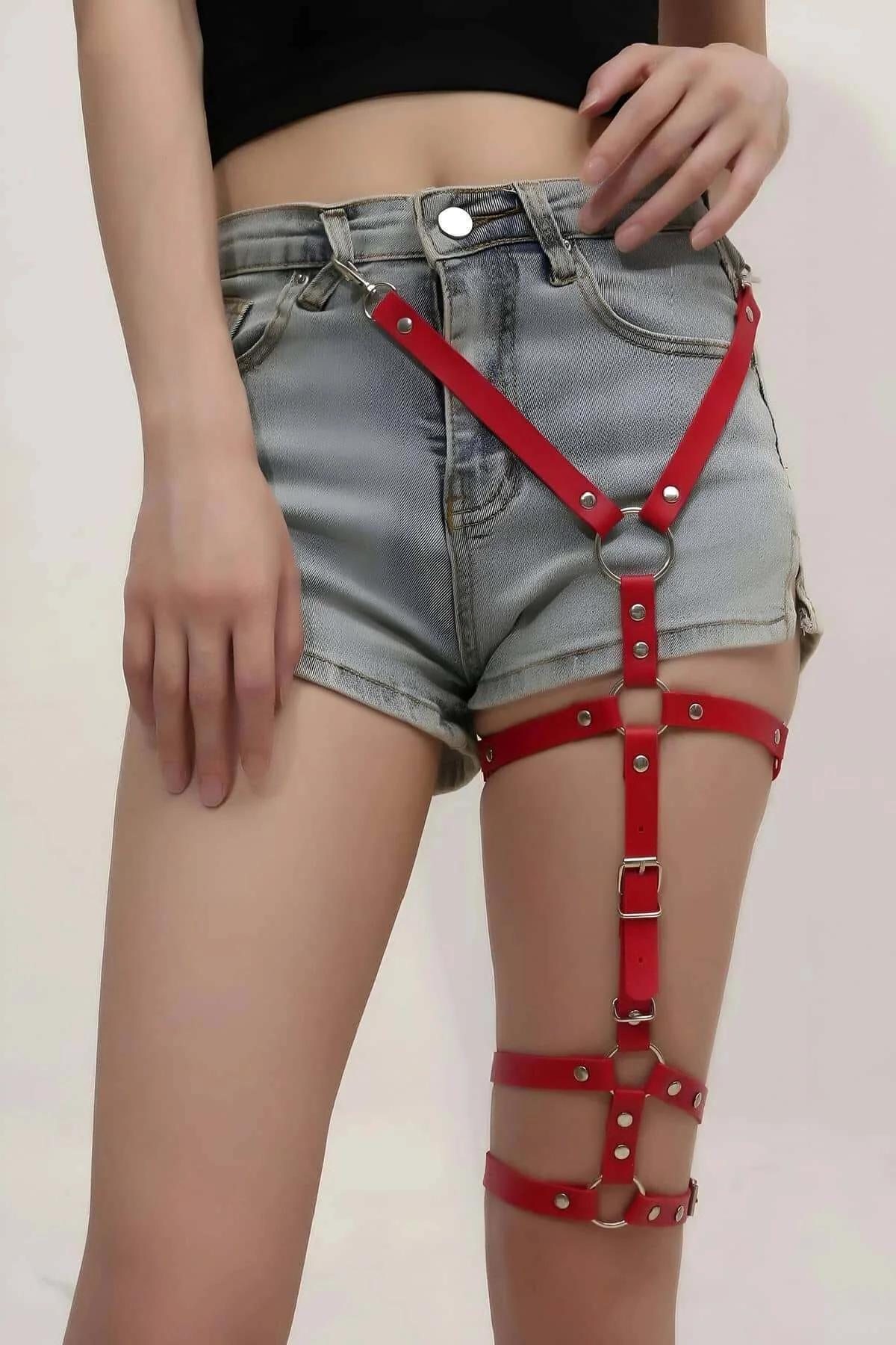 Adjustable red garter harness straps wrapping upper and lower thigh with silver hardware