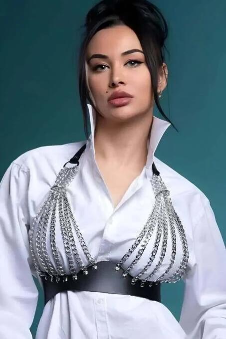 Close-up of silver curb-link chain rows on black faux leather waistband harness