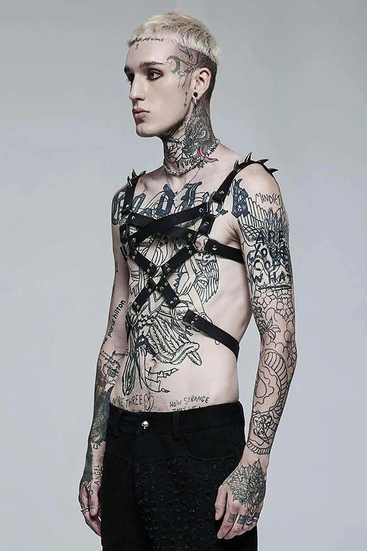 black faux leather harness X-strap configuration across male torso against grey background