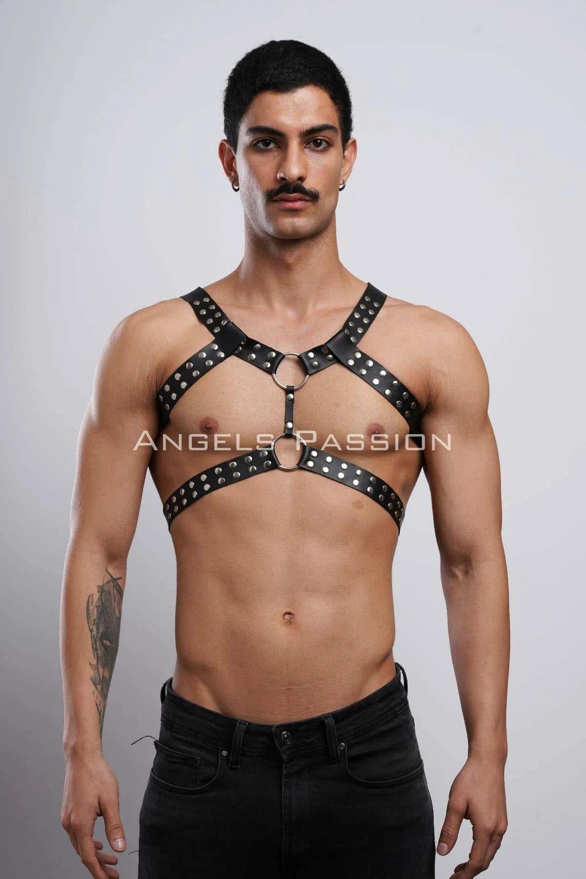 Close-up of silver studs and gold O-ring detail on black faux leather chest harness straps
