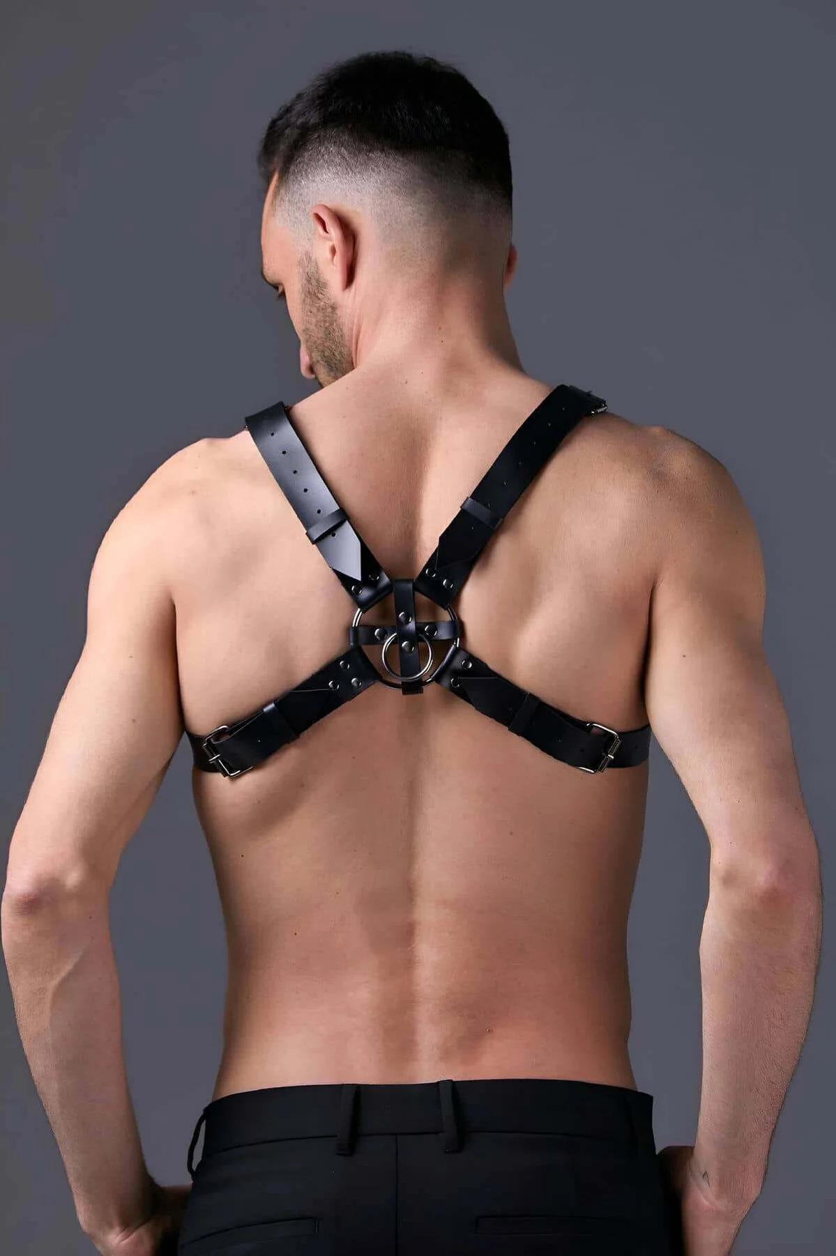 Flat lay of adjustable black faux leather chest harness showing all four buckles and stud rivets