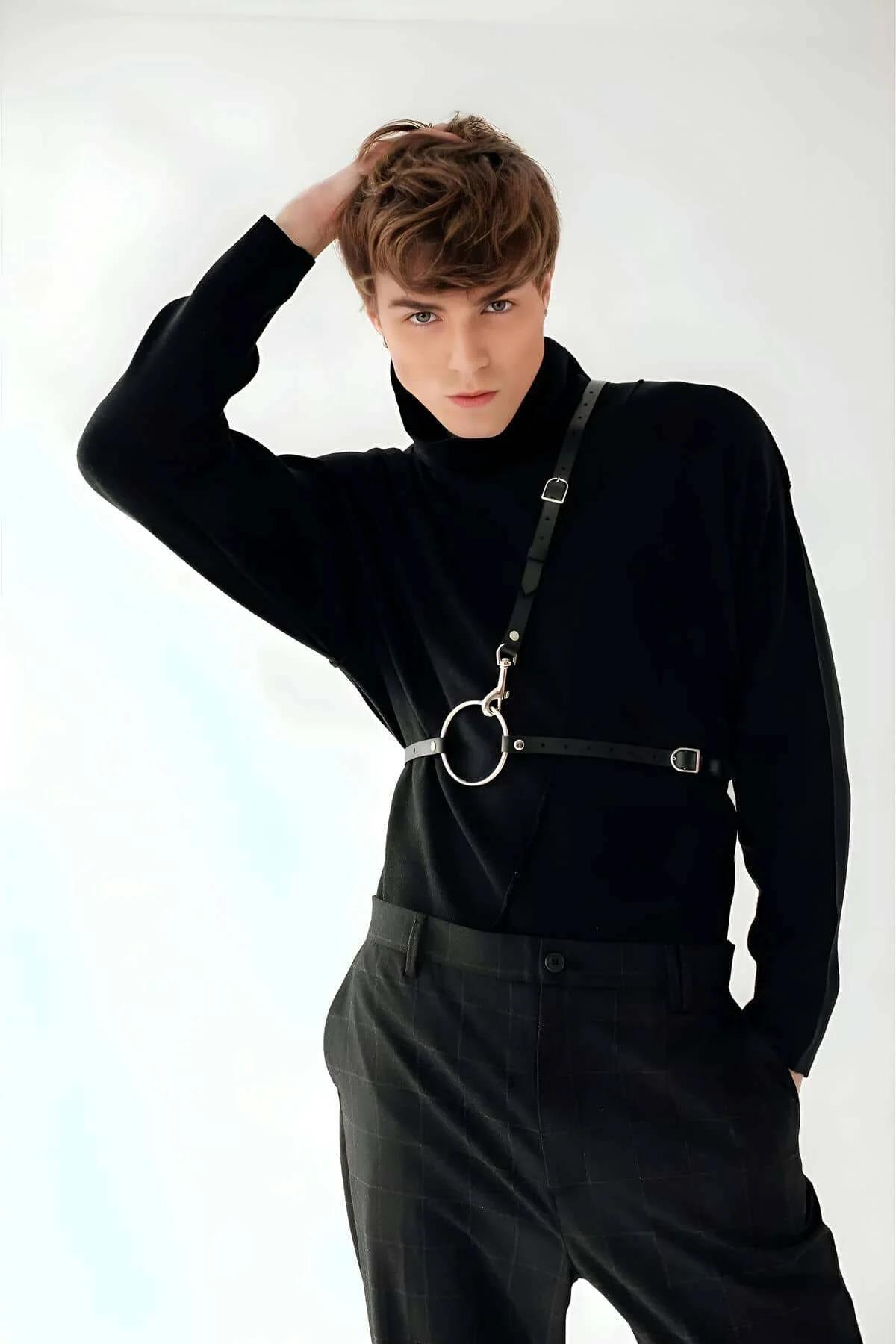 Close-up of silver O-ring and lobster clasp detail on black faux leather men's body harness