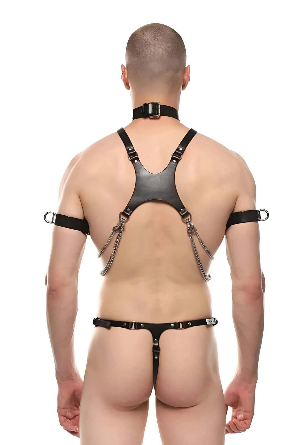 close-up of gold-tone O-ring and three draped chains on black faux leather chest harness