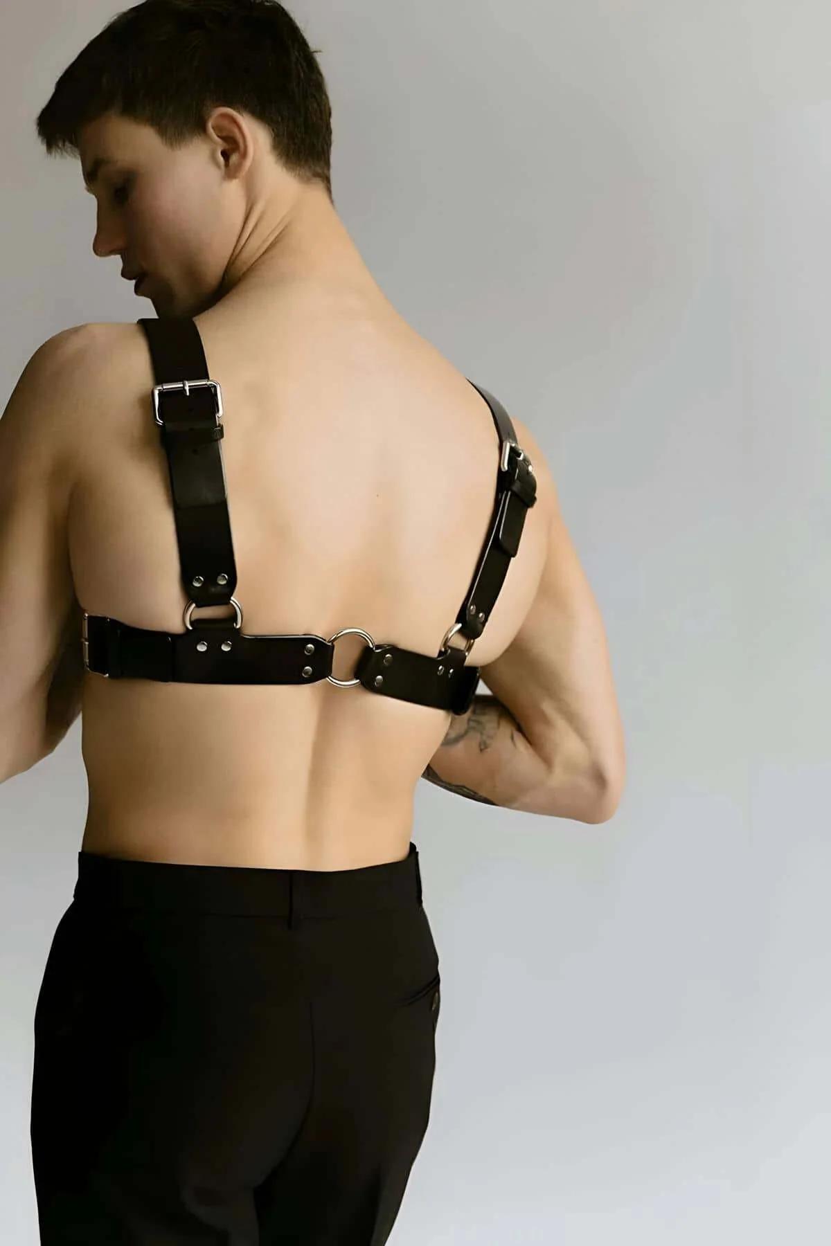 Close-up of silver O-ring and dome-head rivets on black faux leather chest harness center strap