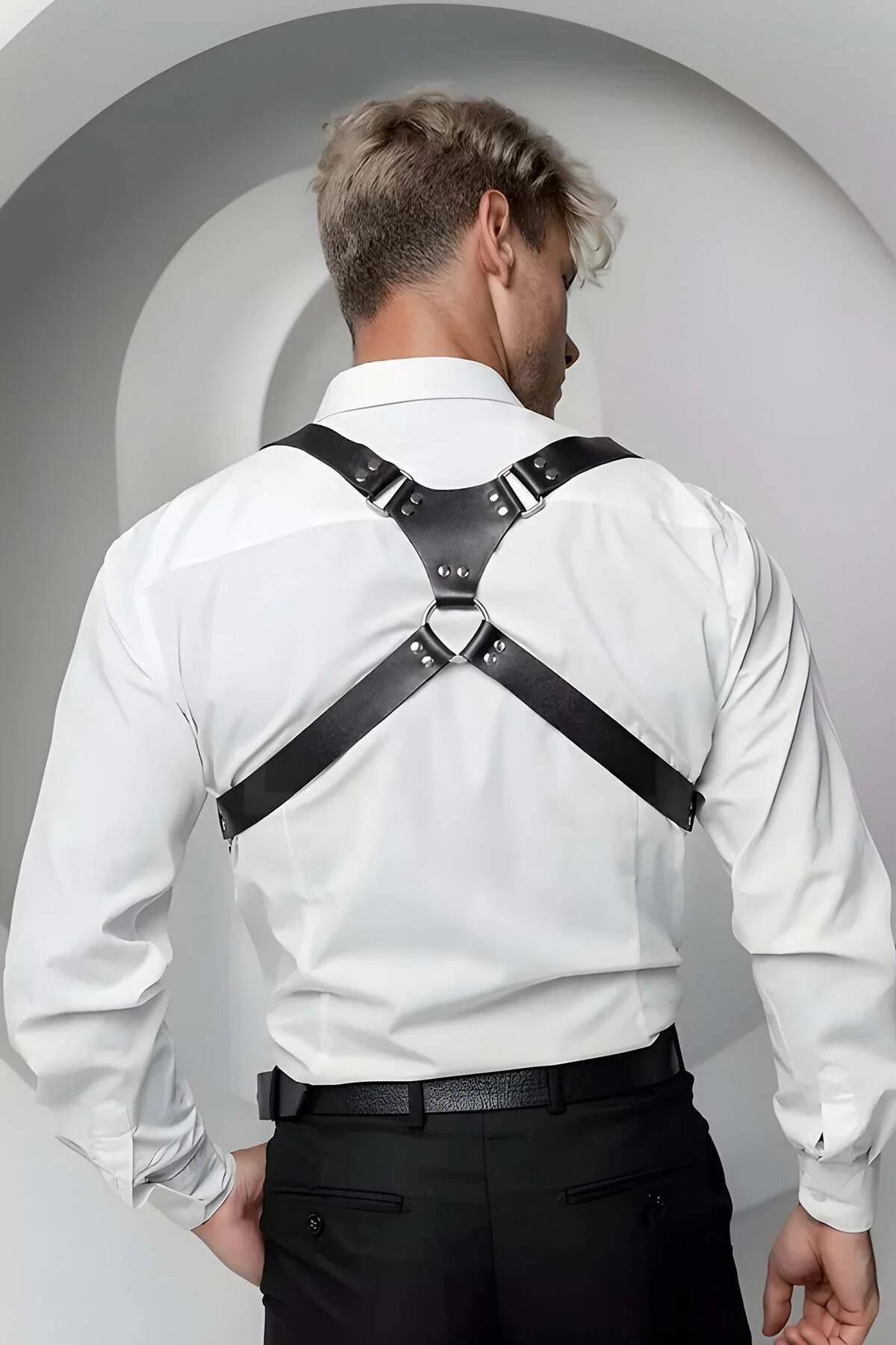 Close-up of silver pin buckle on black faux leather shoulder harness strap, textured grain surface visible