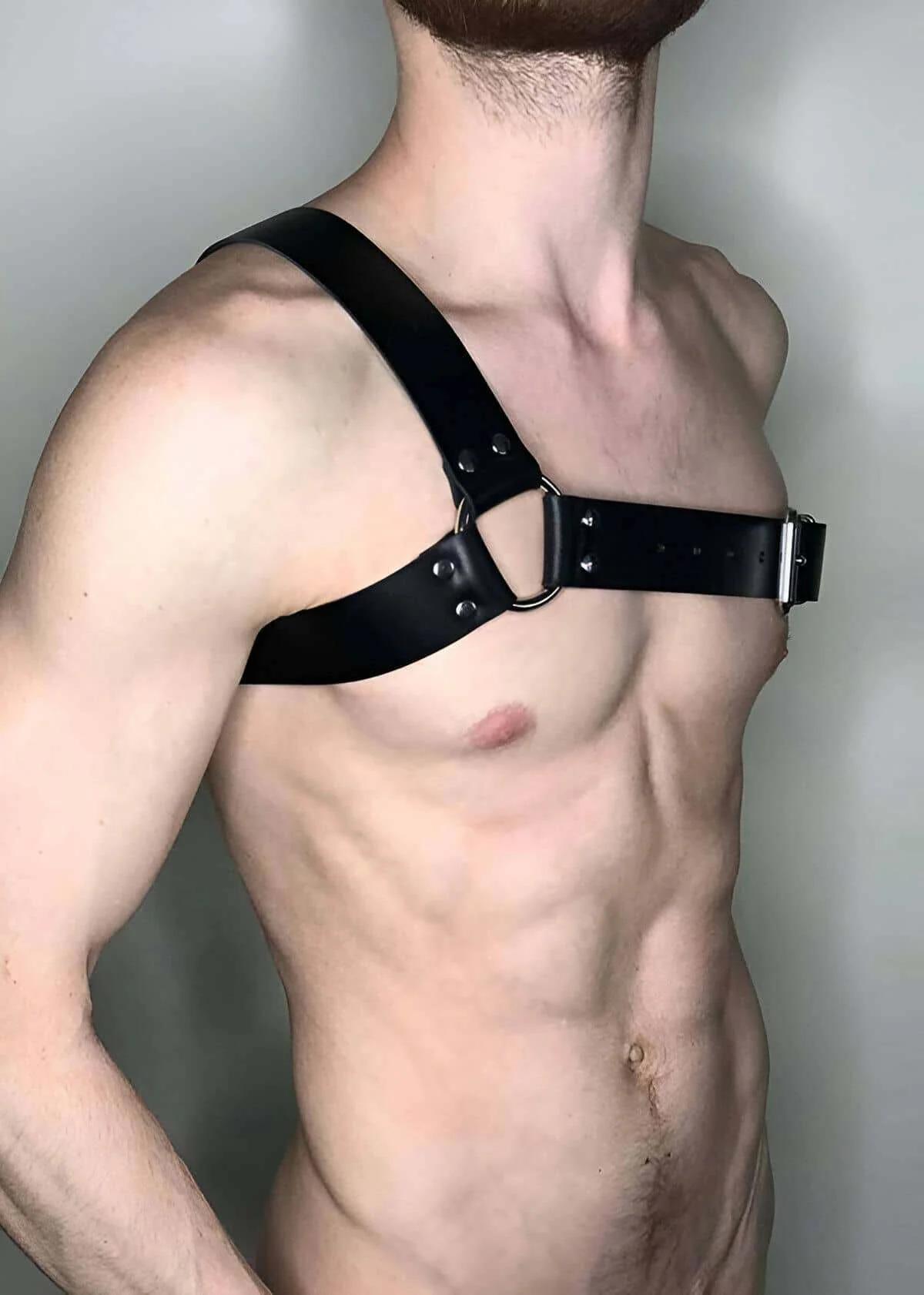 Close-up of silver O-ring rivet detail on black faux leather diagonal chest harness strap