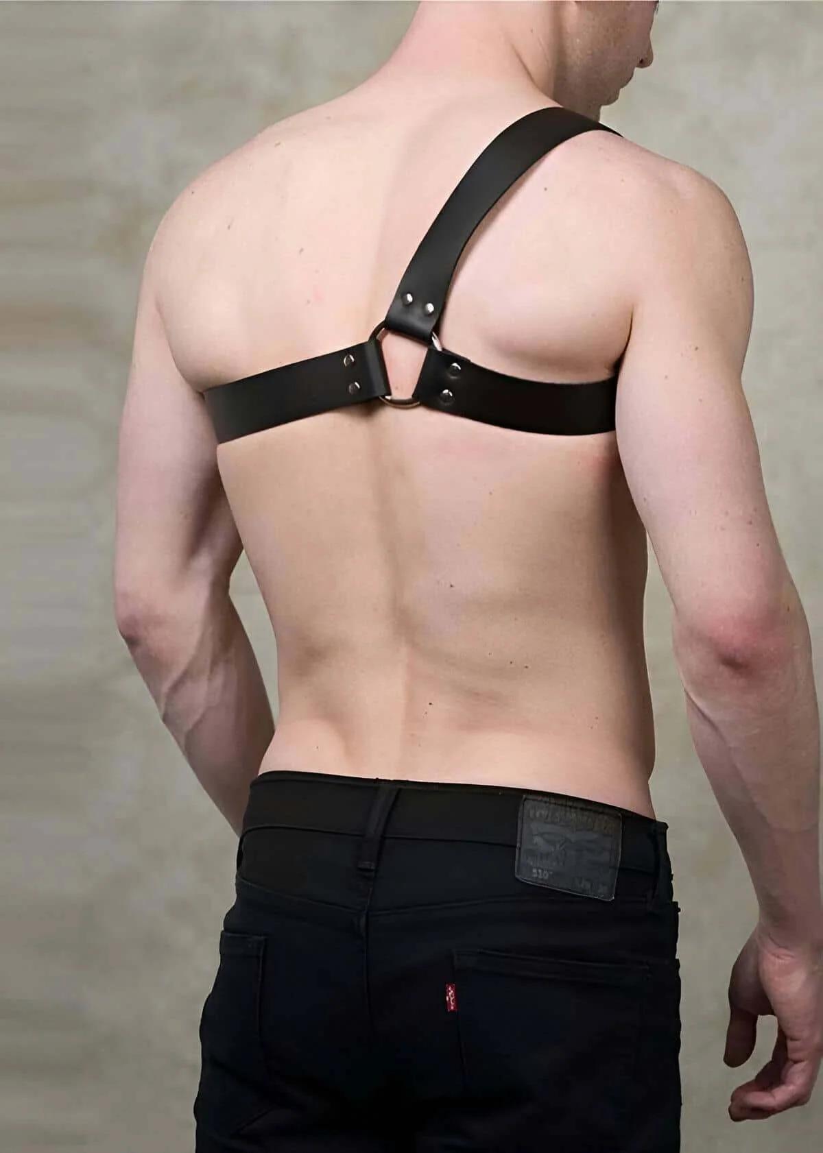 Matte-black rectangular adjustable buckle on right side of black asymmetrical leather chest harness