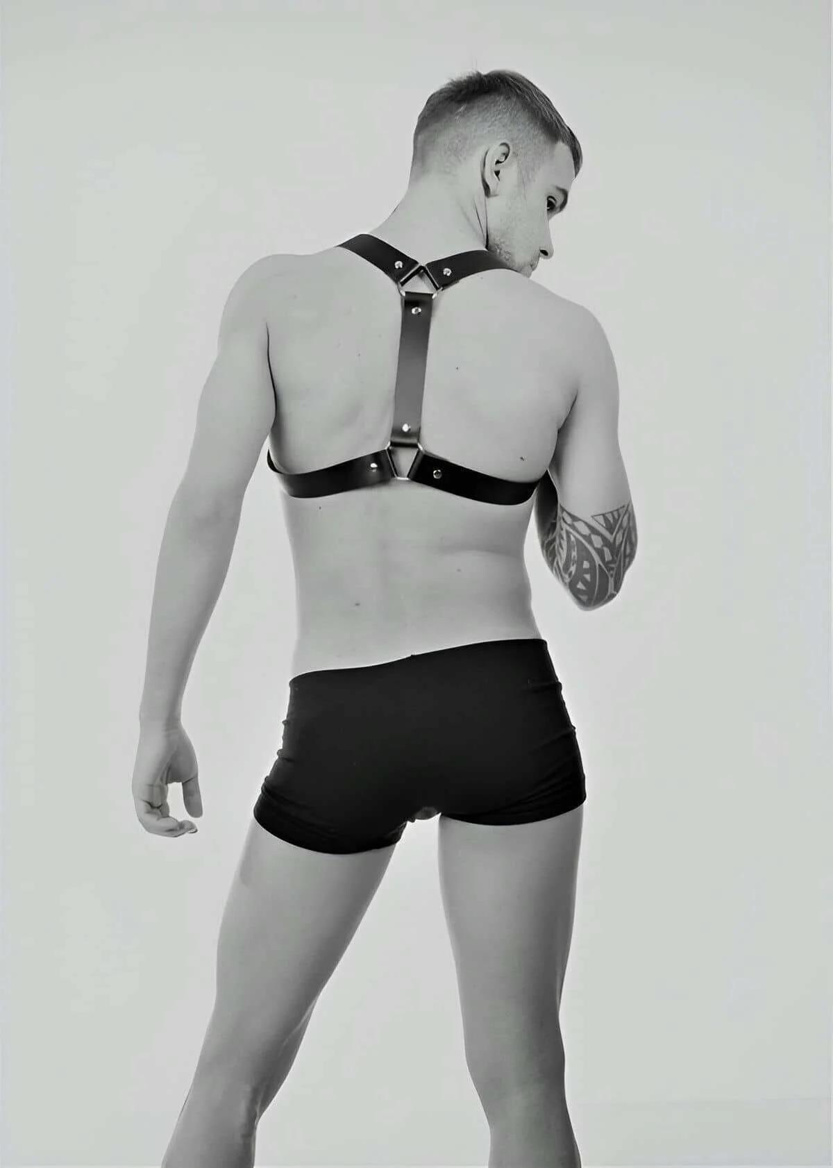 Close-up of silver O-ring and rivet detail on black faux leather shoulder harness strap