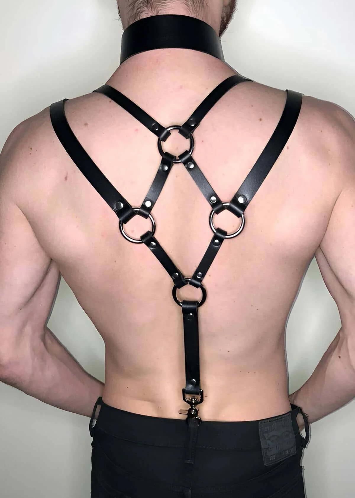 Black faux leather back harness with four silver O-rings and X-cross strap design, worn with matching wide collar