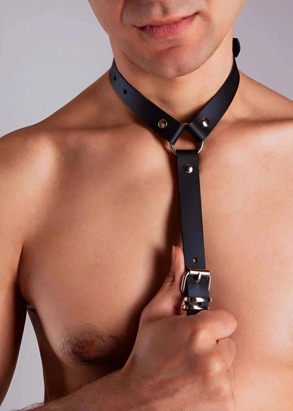Gold-tone O-ring at waist band of black PU shoulder harness against bare torso