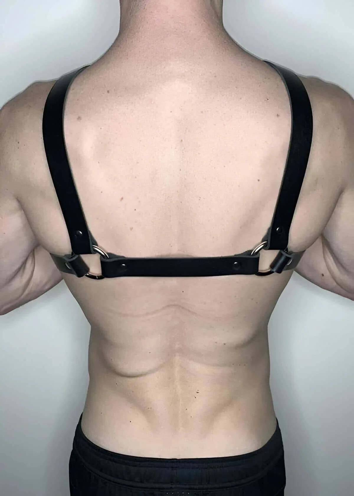 close-up of silver O-ring junction and rivet studs on black faux leather chest harness