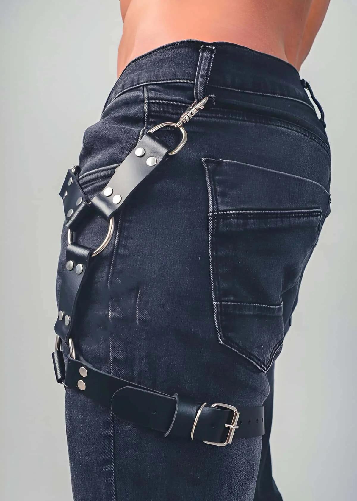 Close-up of silver O-ring and lobster clasp detail on black faux leather thigh harness strap