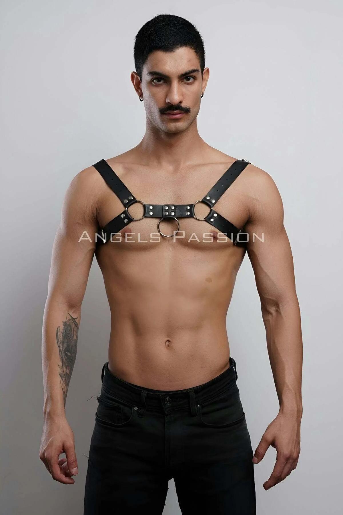 black faux leather adjustable chest harness with three gold O-rings and silver stud rivets worn by a male model