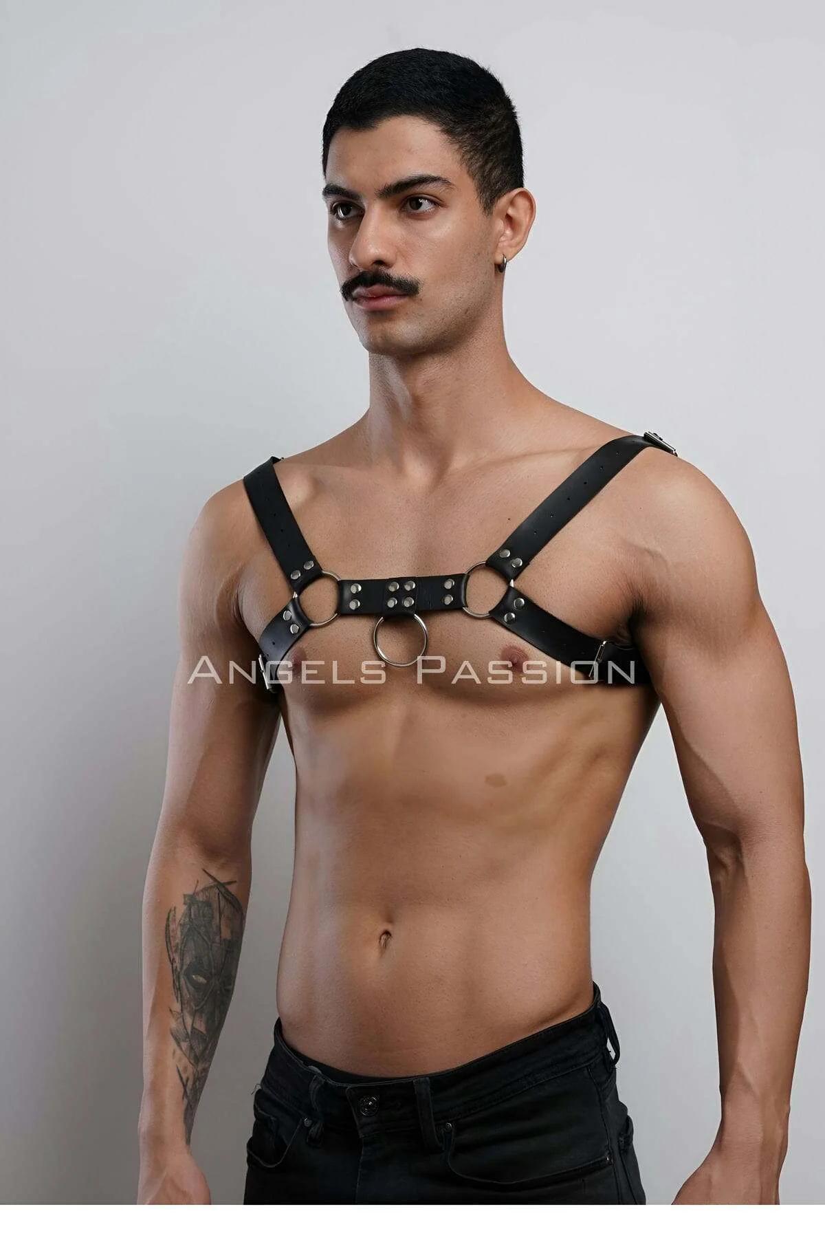 close-up of gold O-rings and silver stud rivets on black faux leather chest harness strap detail