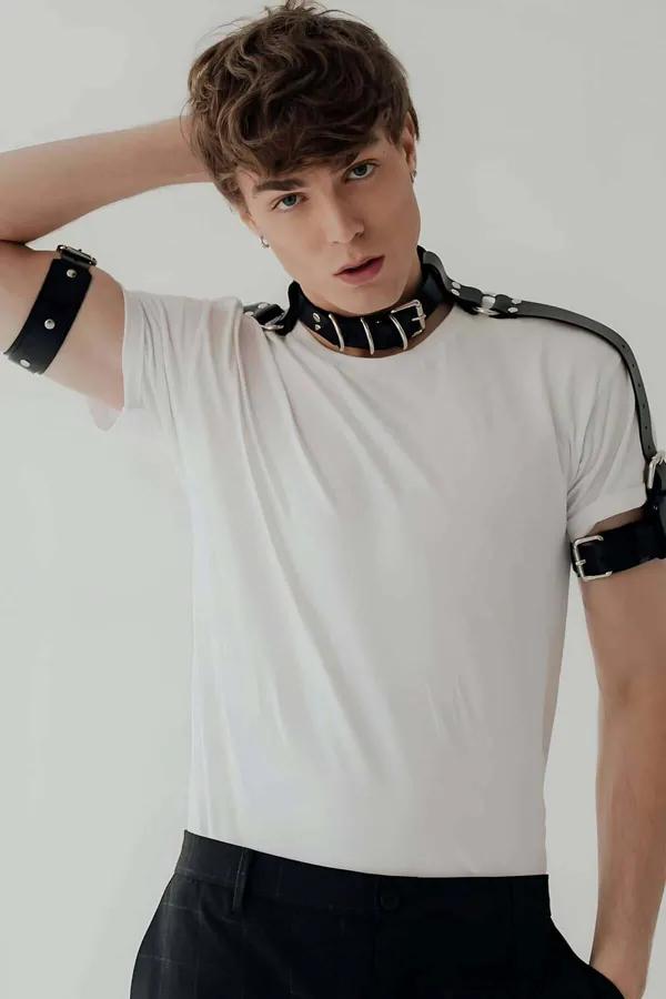 black faux leather neck collar harness with silver D-rings and matching bicep cuffs worn over white tee