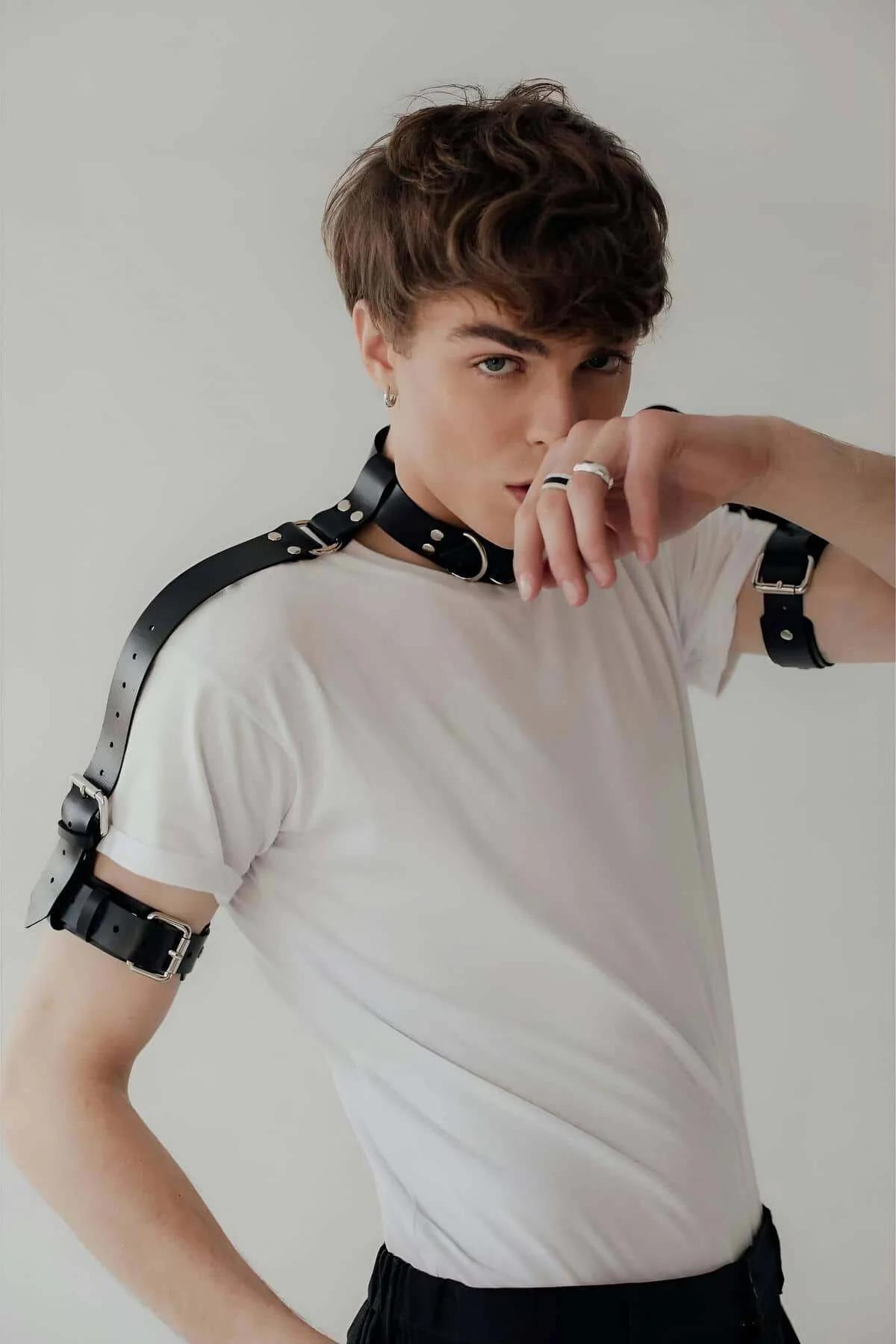 rear view of black faux leather shoulder strap harness connecting neck collar to arm cuffs
