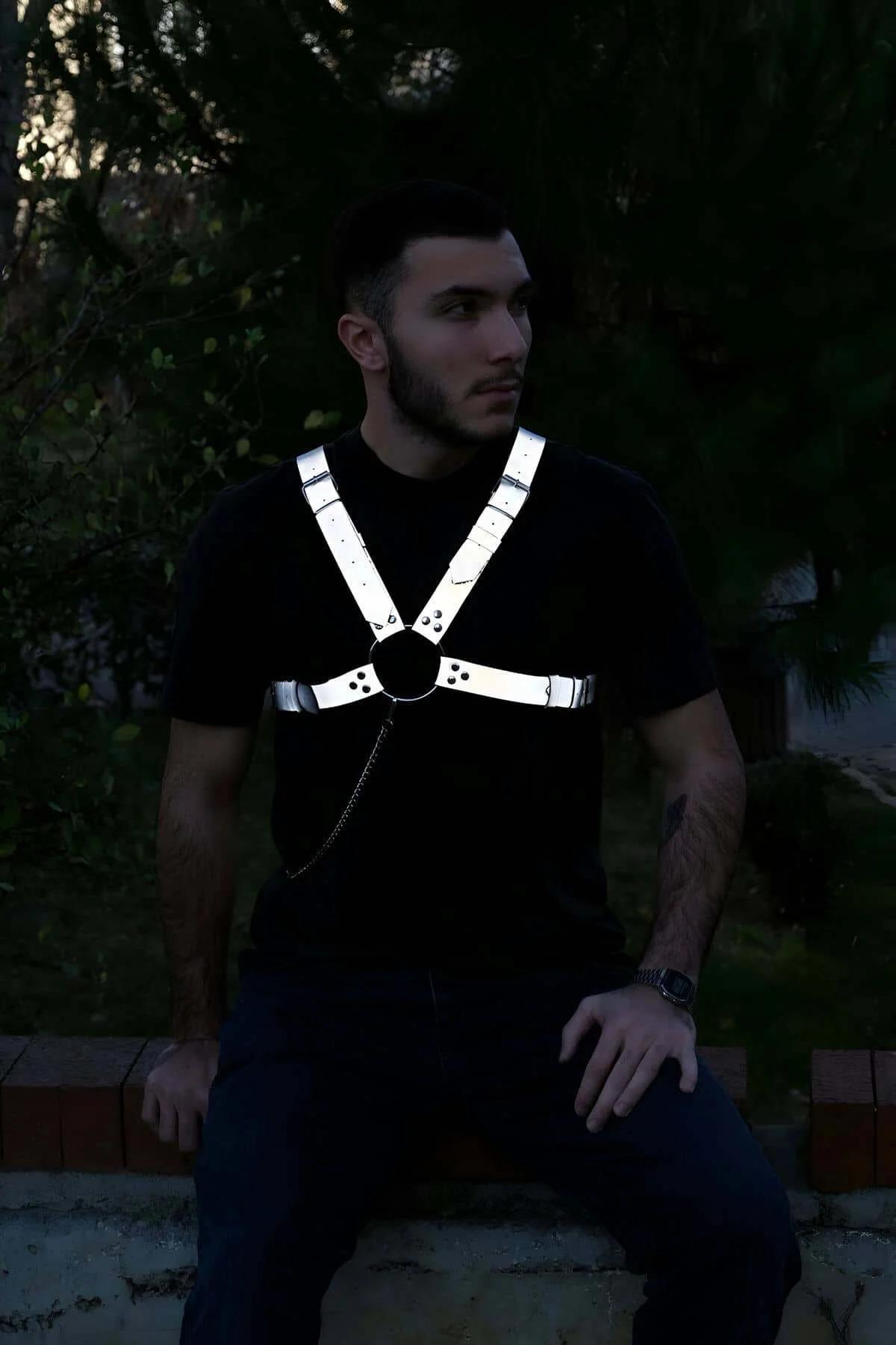 Close-up of reflective white fabric straps and rivet stud details on men's chest harness