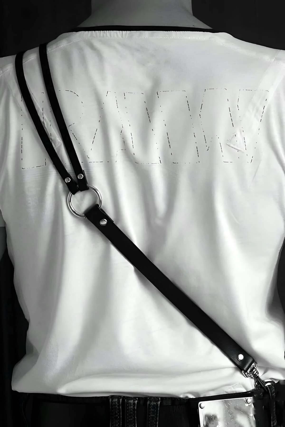 black faux leather chest harness layered over white crew-neck t-shirt street style