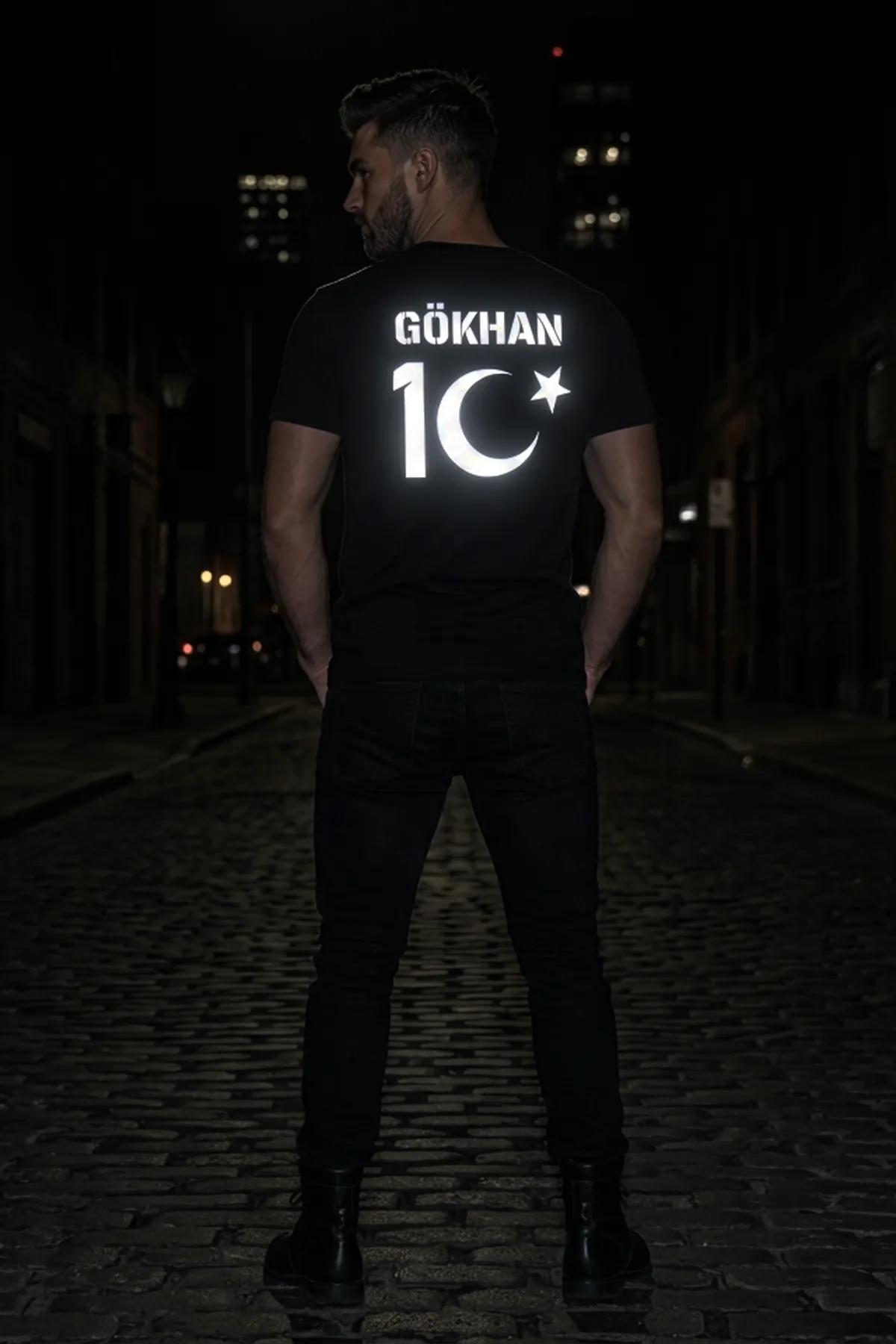 black men's reflective t-shirt with silver-white GÖKHAN 10 crescent and star back print worn on a night street