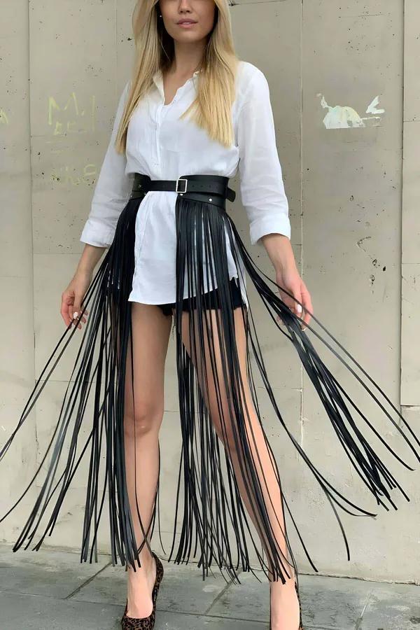 black faux leather fringe waist belt skirt with long tassels and adjustable buckle worn over white shirt and shorts