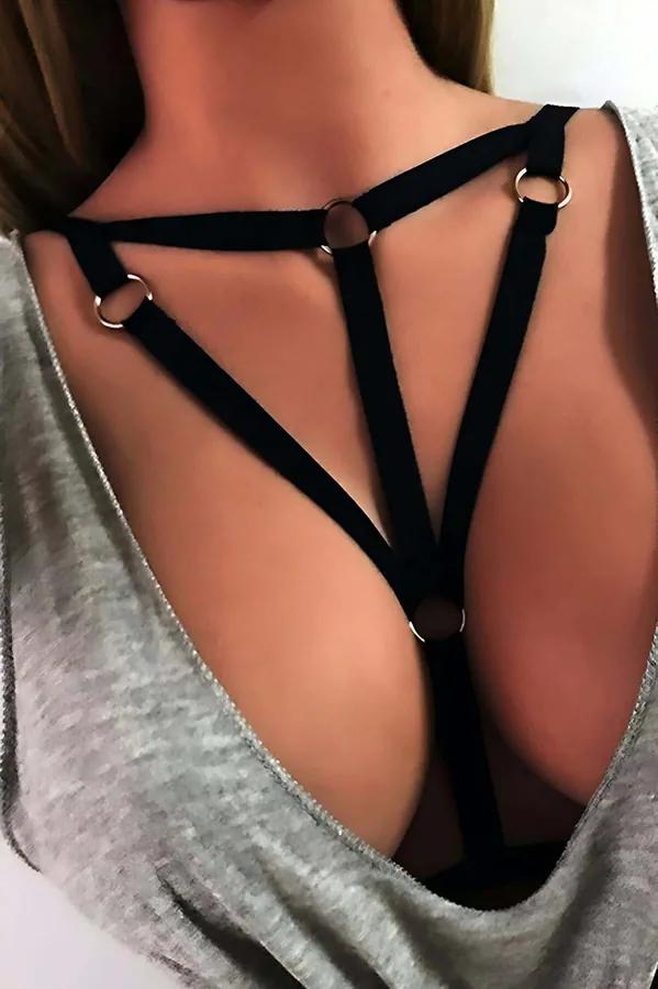 Black elastic chest harness with silver O-rings in triangular cage strap layout worn over grey top