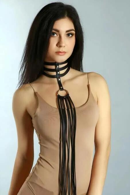Black faux leather triple-strap choker with gold O-ring and long detachable tassel fringe chain, front view on model
