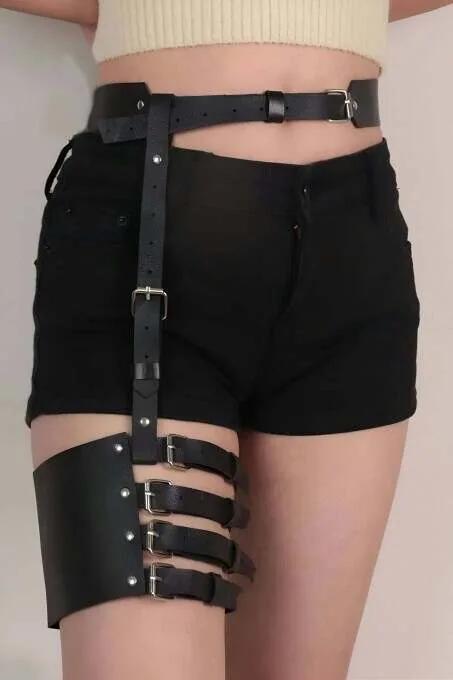 Black faux leather garter harness with four-buckle thigh cuff and adjustable waist belt worn over black shorts
