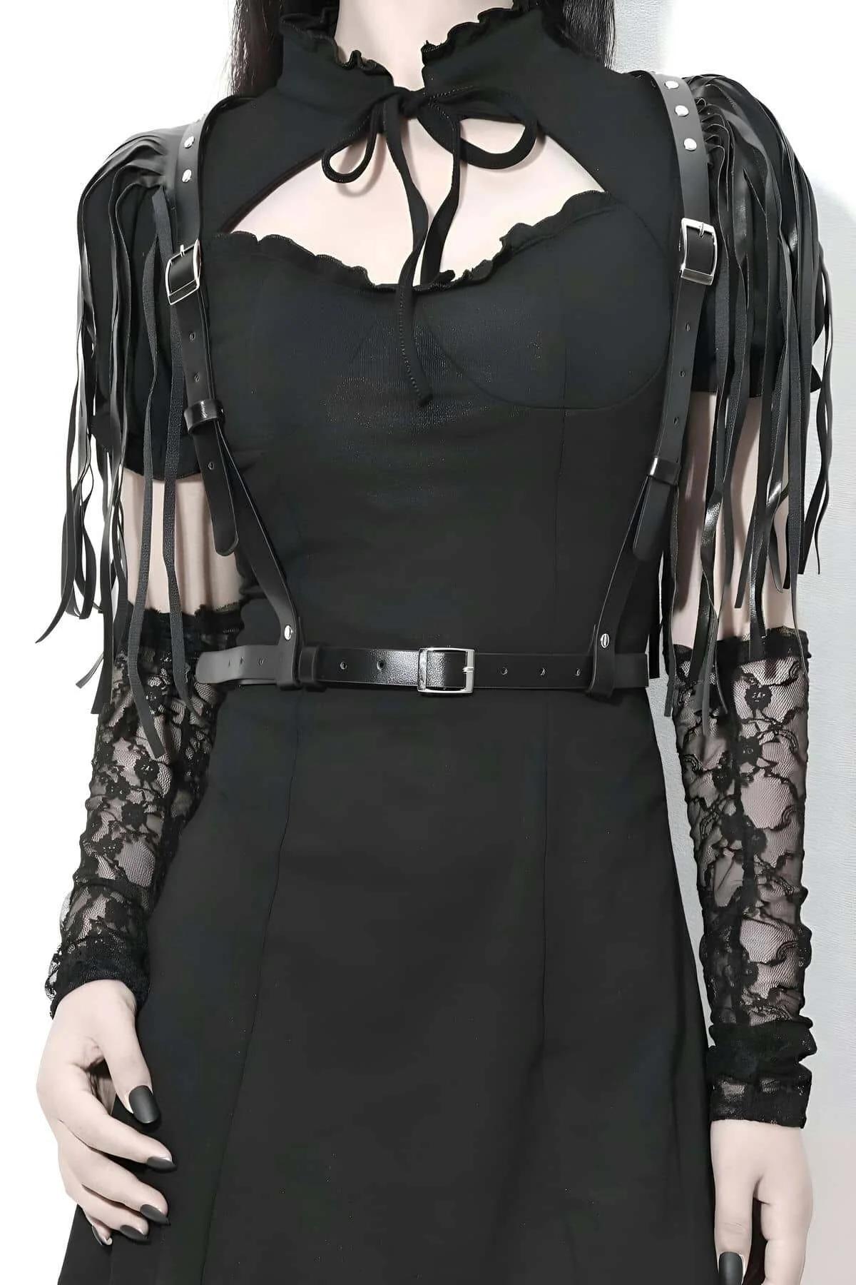 Black faux leather body harness with long fringe shoulder straps and silver-tone buckle waist band worn over black top